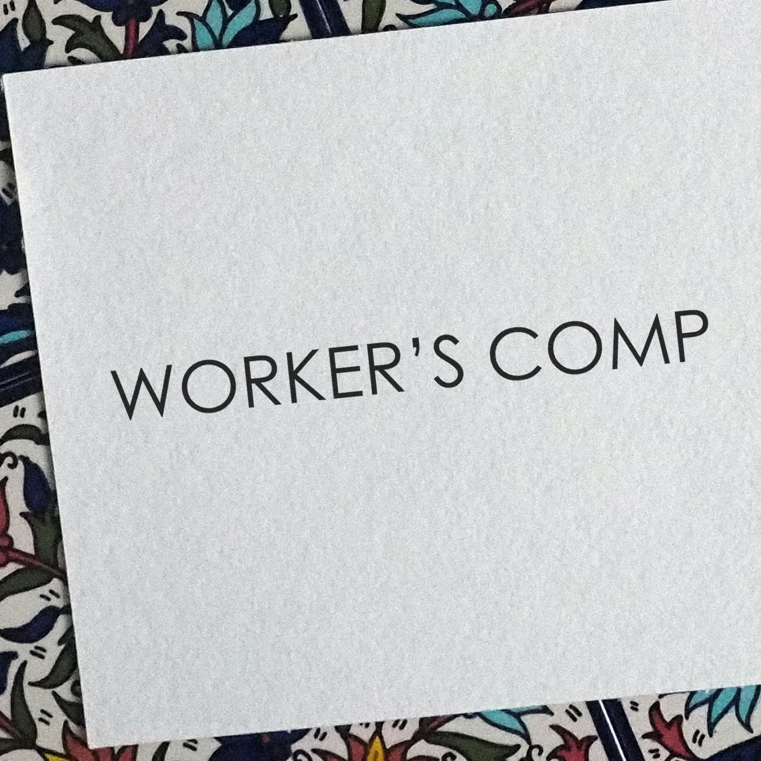 White envelope labeled Workers Comp on a colorful patterned background.
