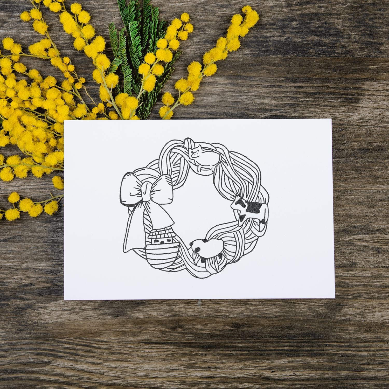 Hand-drawn spring wreath illustration card with yellow mimosa flowers on rustic wood background.