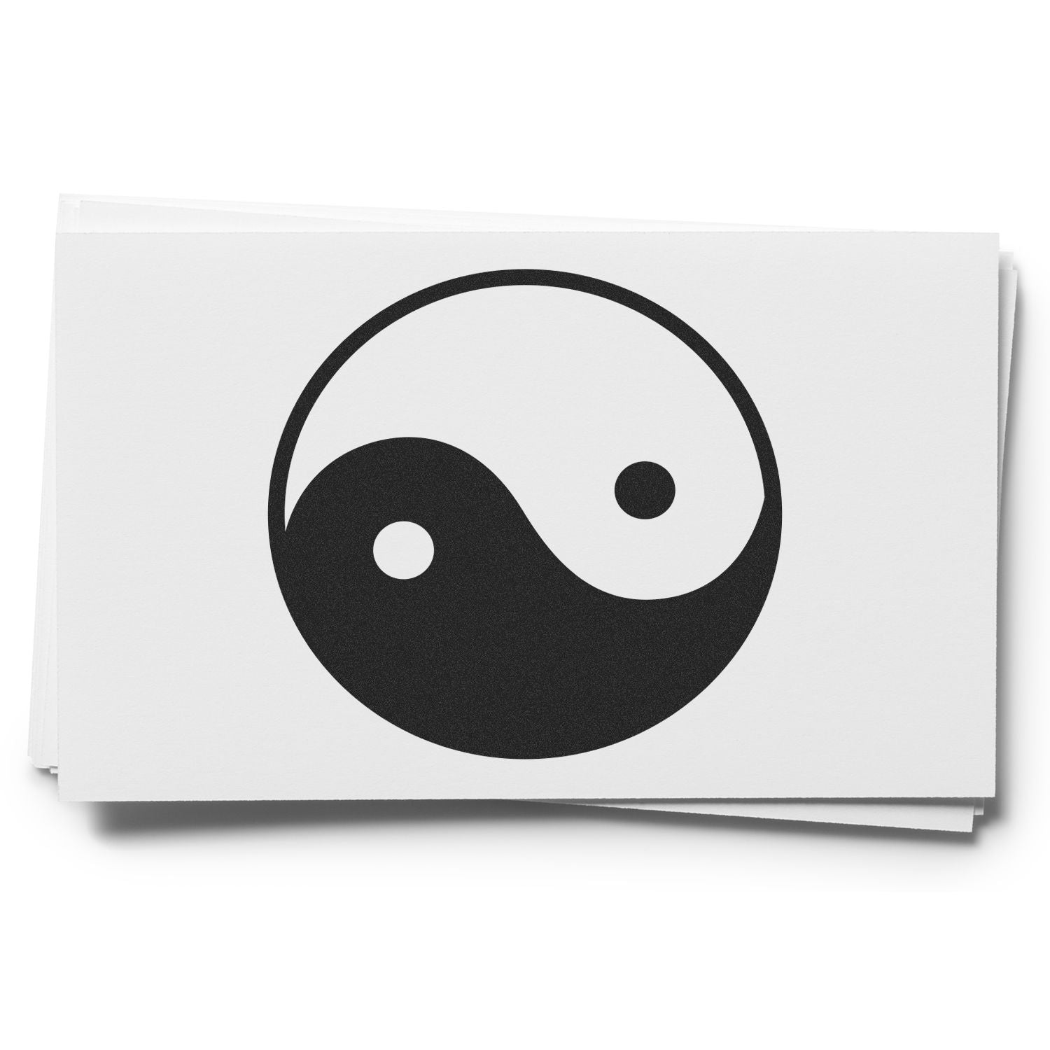 Black yin yang symbol printed on a stack of white business cards, minimalist monochrome design on a clean background.