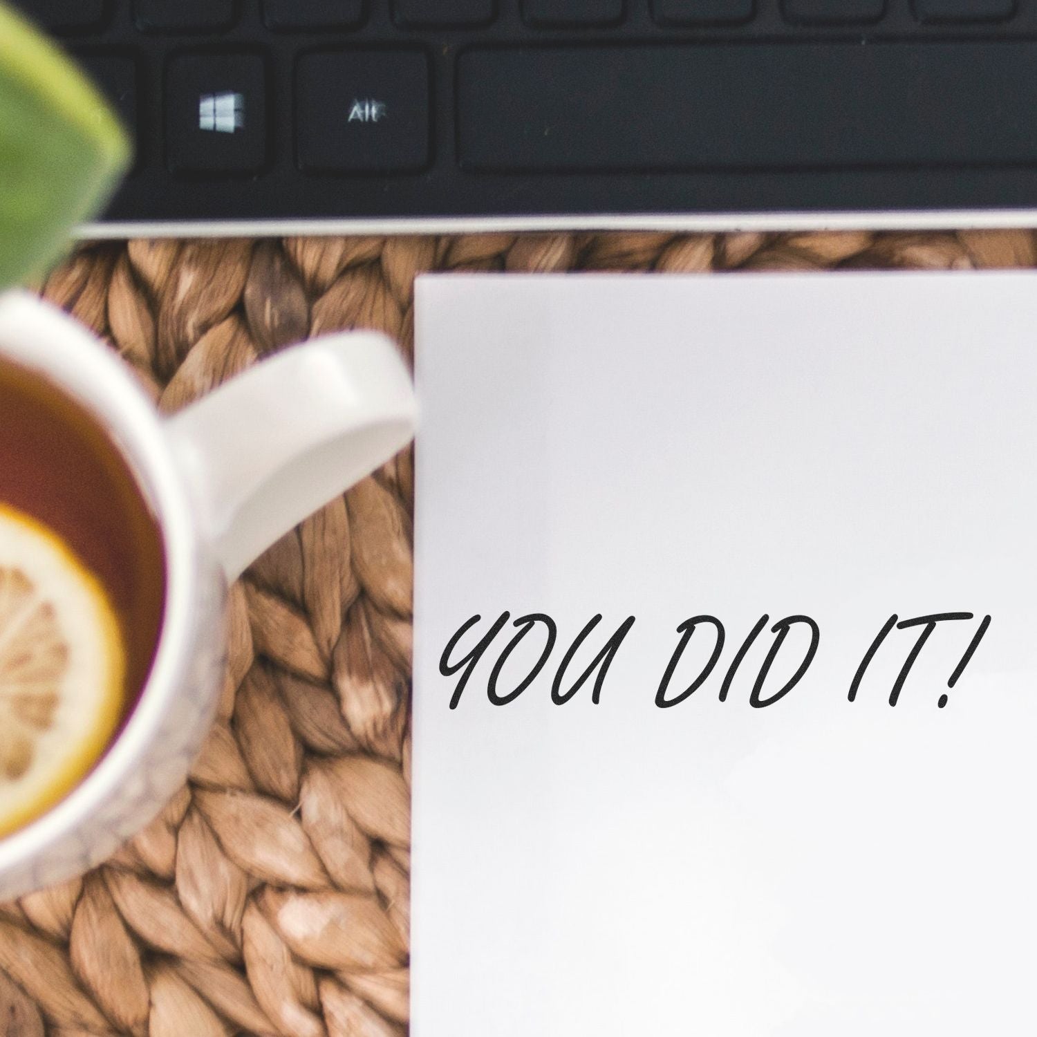 Coffee mug beside laptop and note reading You Did It! on a desk