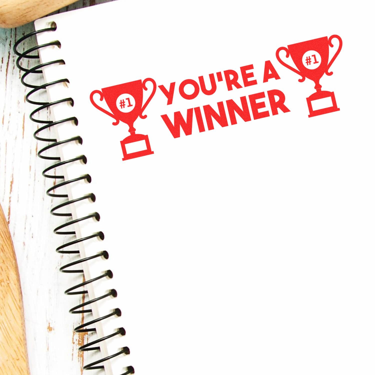 Spiral notebook page with red Youre a Winner text and trophy icons, celebrating success and achievement.