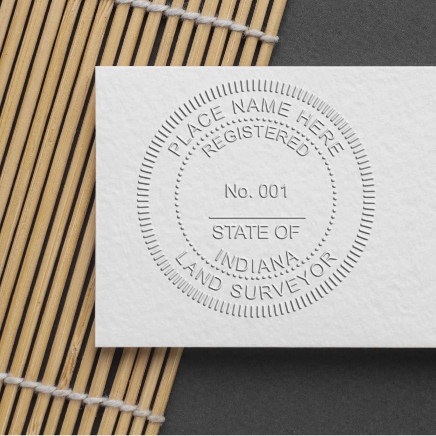 Embossed State of Indiana land surveyor seal on white paper with bamboo mat background