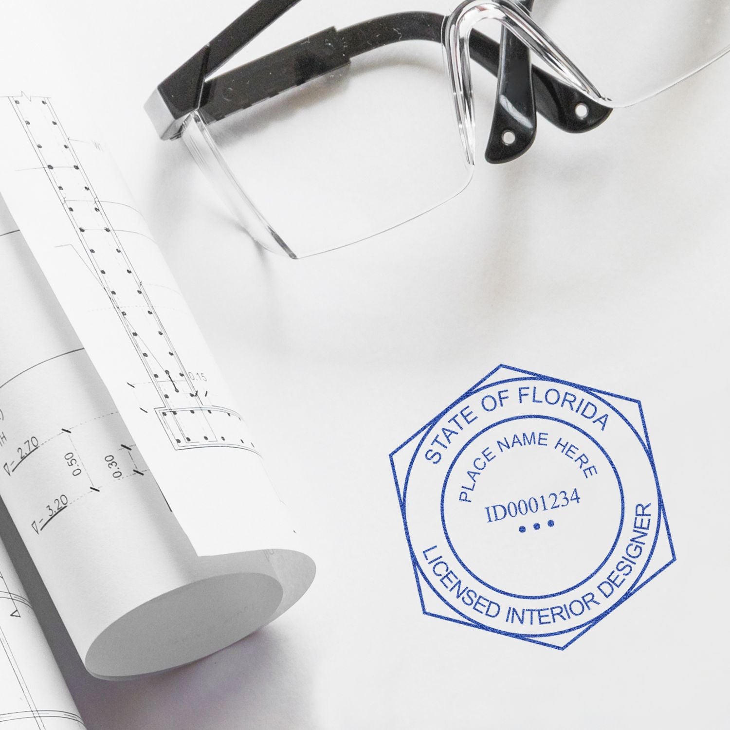 Architectural blueprints with eyeglasses and Florida licensed interior designer stamp on a design plan.