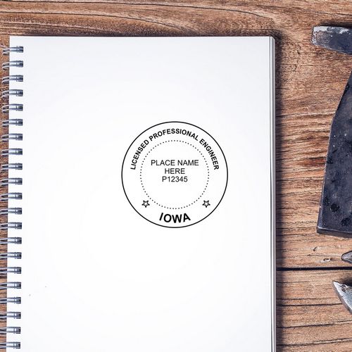 Iowa licensed professional engineer stamp on a blank spiral notebook on a wooden desk.