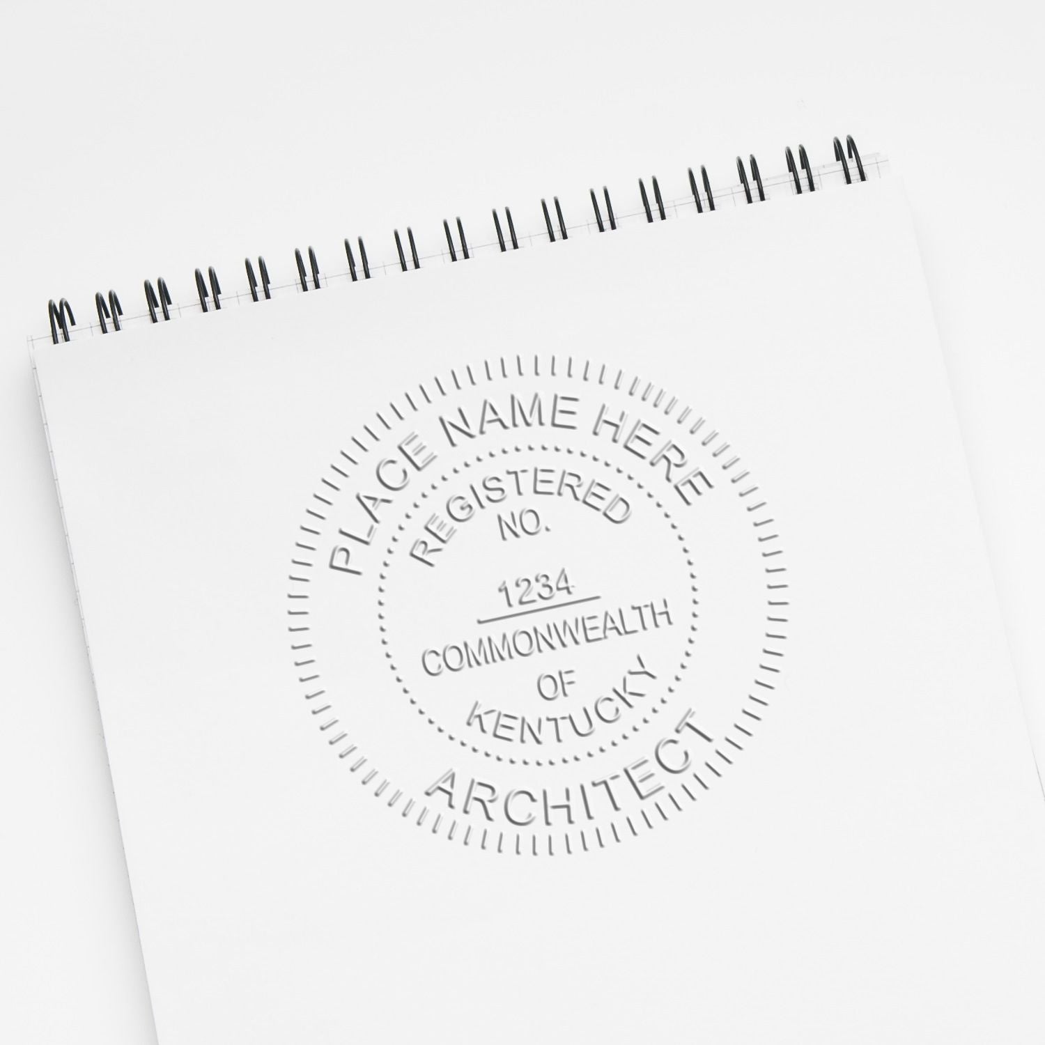Blank spiral notebook with embossed Commonwealth of Kentucky architect seal on white cover, minimal office stationery mockup.