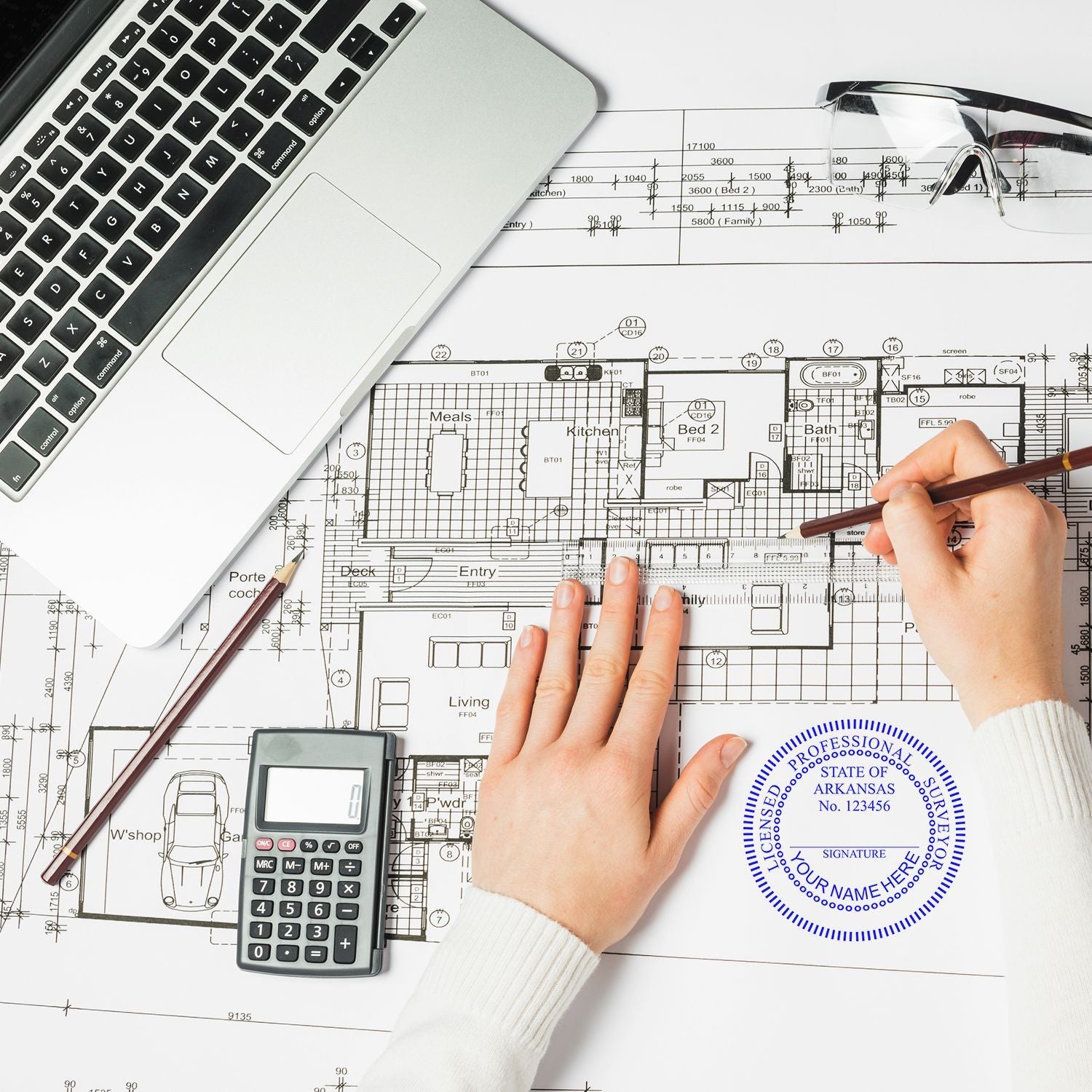 Architectural blueprint review with laptop, calculator, ruler, and hands drafting a house floor plan.