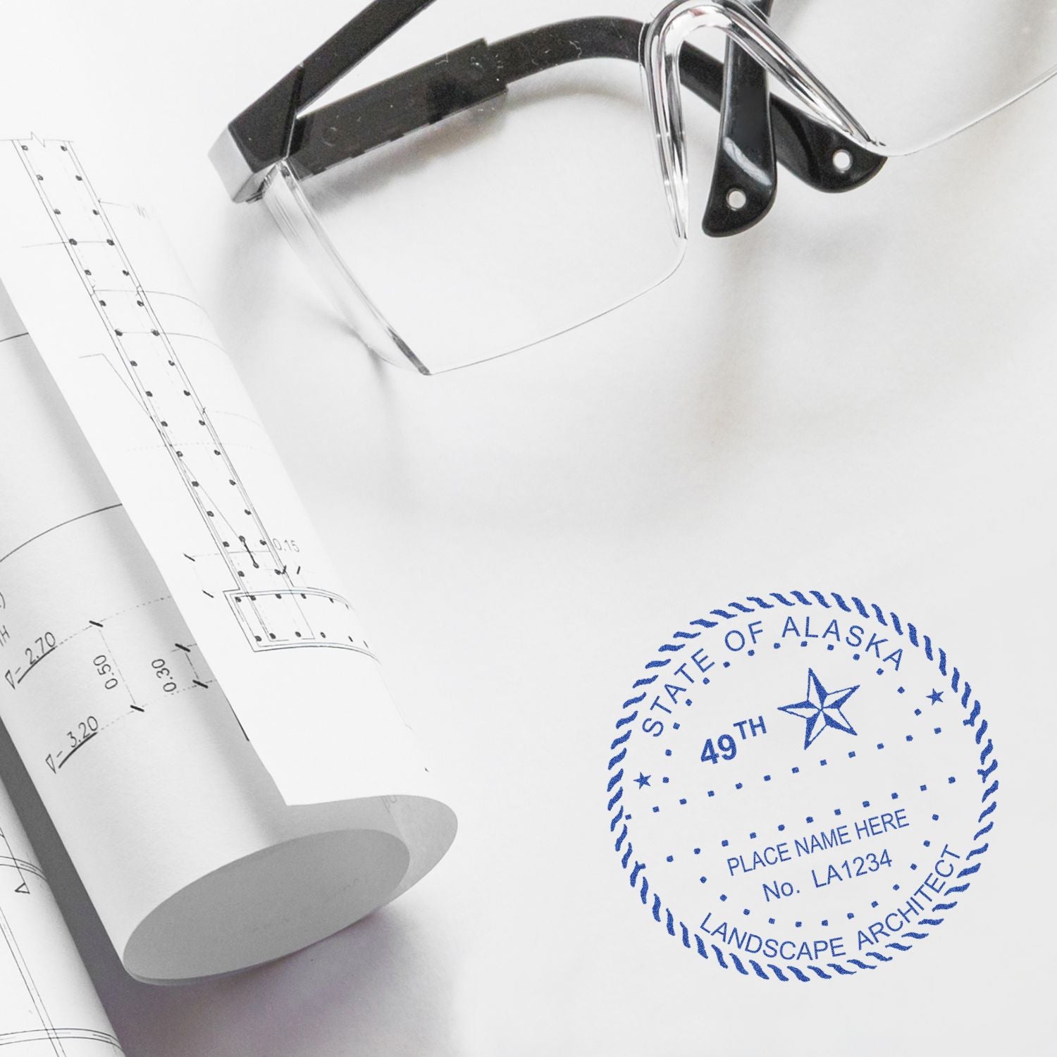 Architectural blueprint with eyeglasses and Alaska landscape architect stamp on white paper.