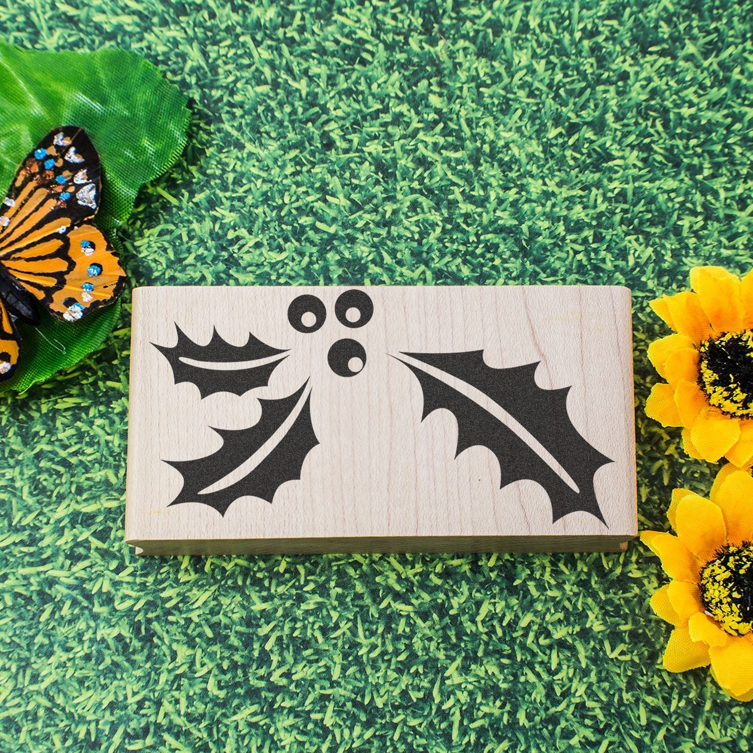 Halloween bat decoration on wooden block with butterfly and sunflower on green grass background