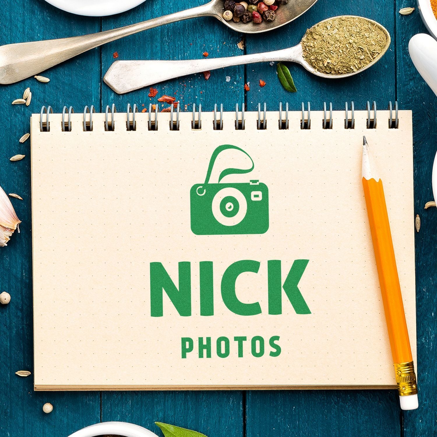 Flat lay notebook labeled Nick Photos with green camera icon on blue wooden background, representing photography inspiration.
