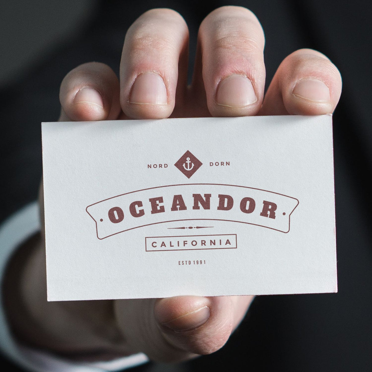 Close-up of fingers holding Oceandorr California packaging label with nautical anchor emblem and Est. 1991 mark.