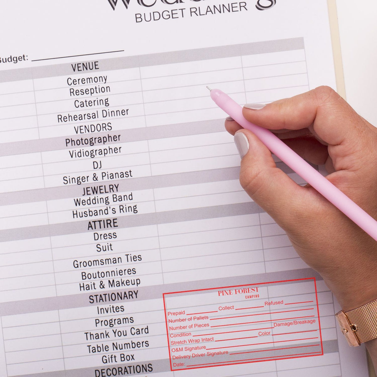 Hand with pink pen filling a wedding budget planner checklist for venue, vendors, attire, and catering essentials.