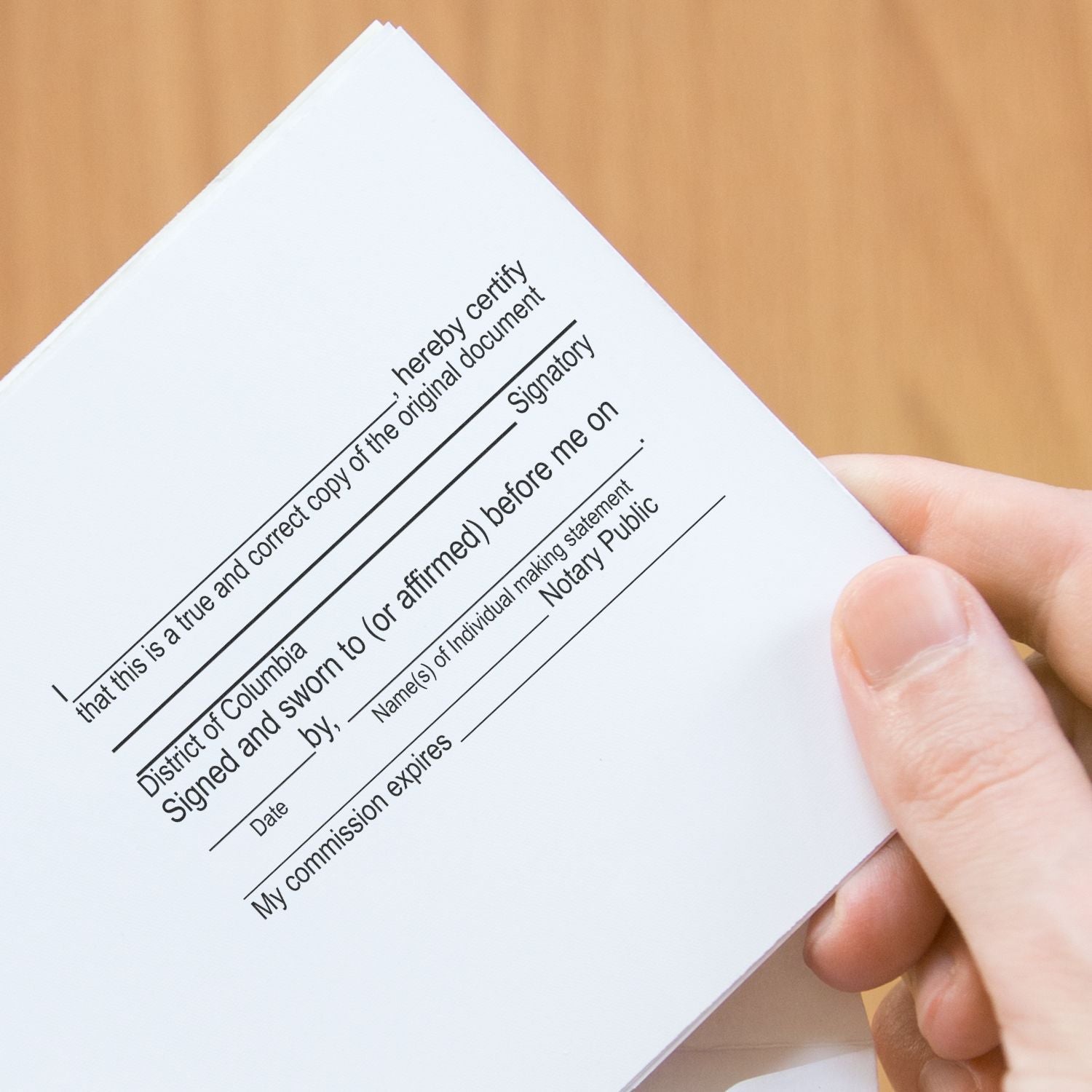 Hand holding a notarized certification document with hereby certify text and signature lines, legal affidavit verification