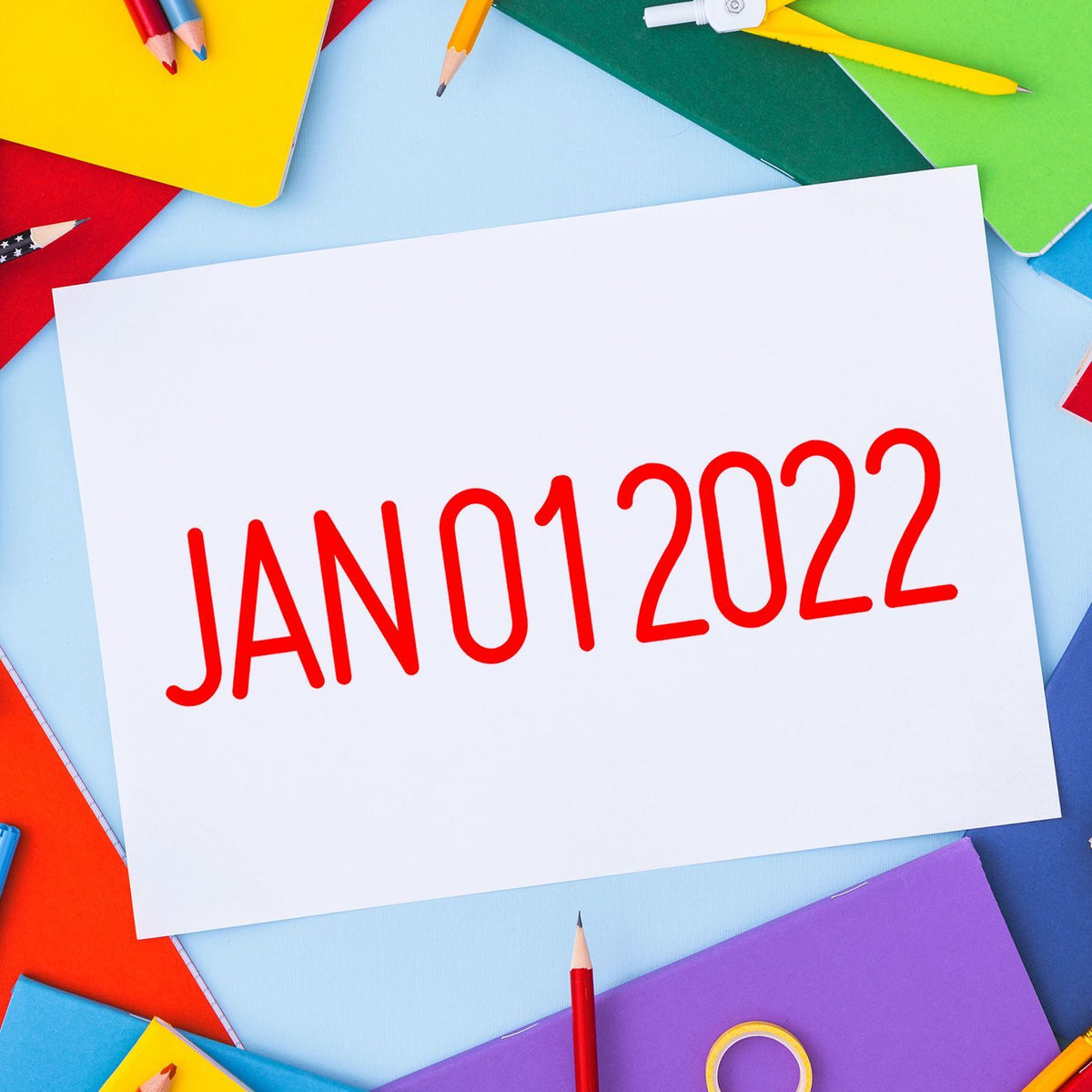 Colorful stationery surrounding a white paper with JAN 01 2022 text, concept for New Year, calendar, and back-to-school planning.