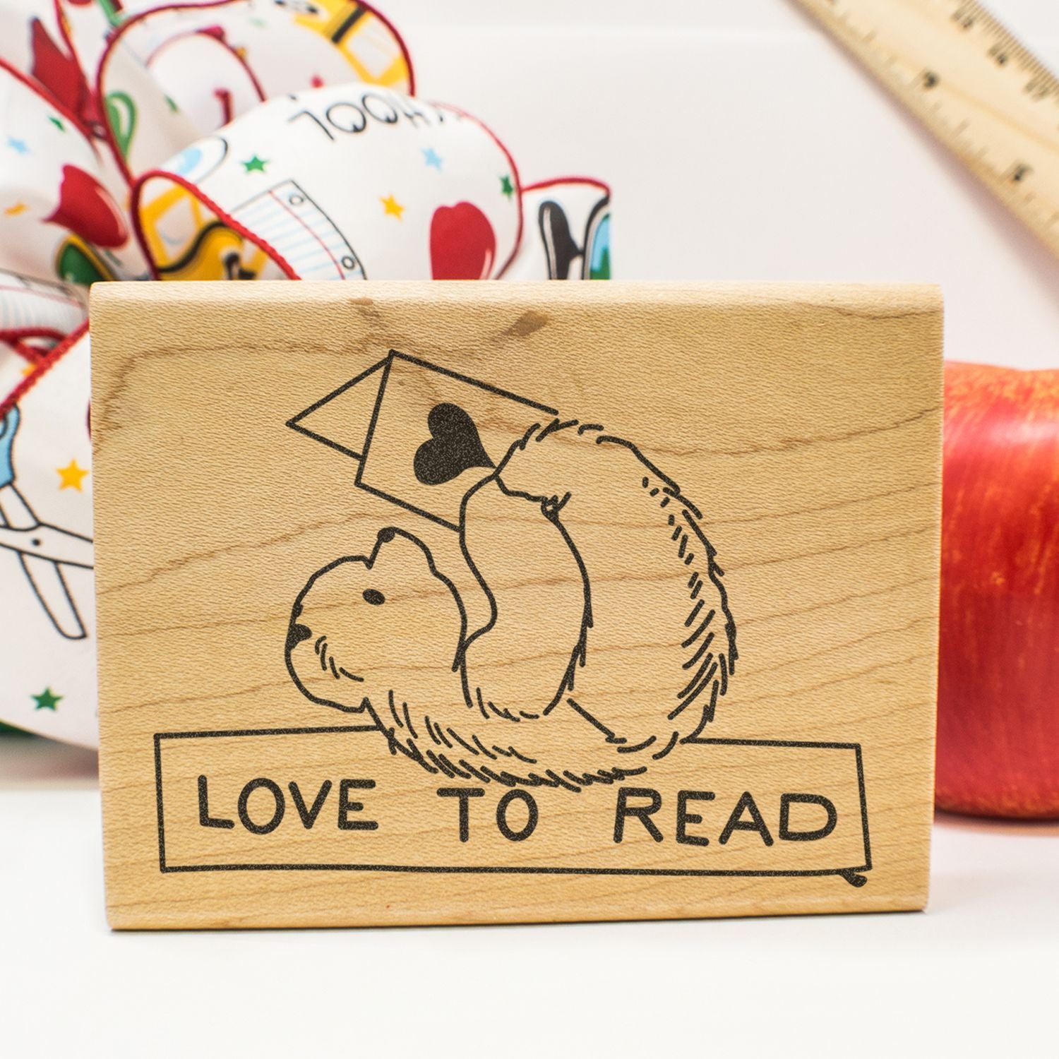 Wooden Love to Read stamp with bear illustration, books, and craft supplies background