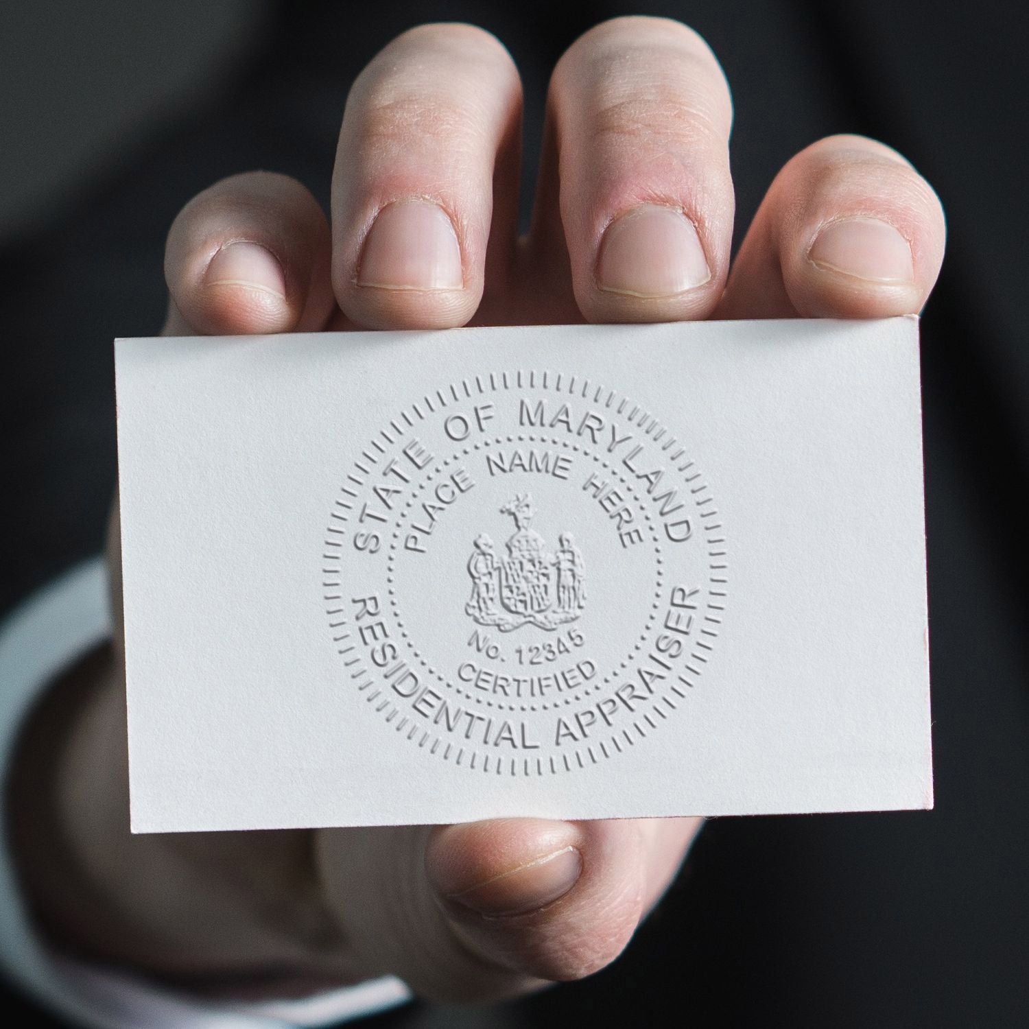 Hand holding an embossed State of Maryland residential appraiser certificate card