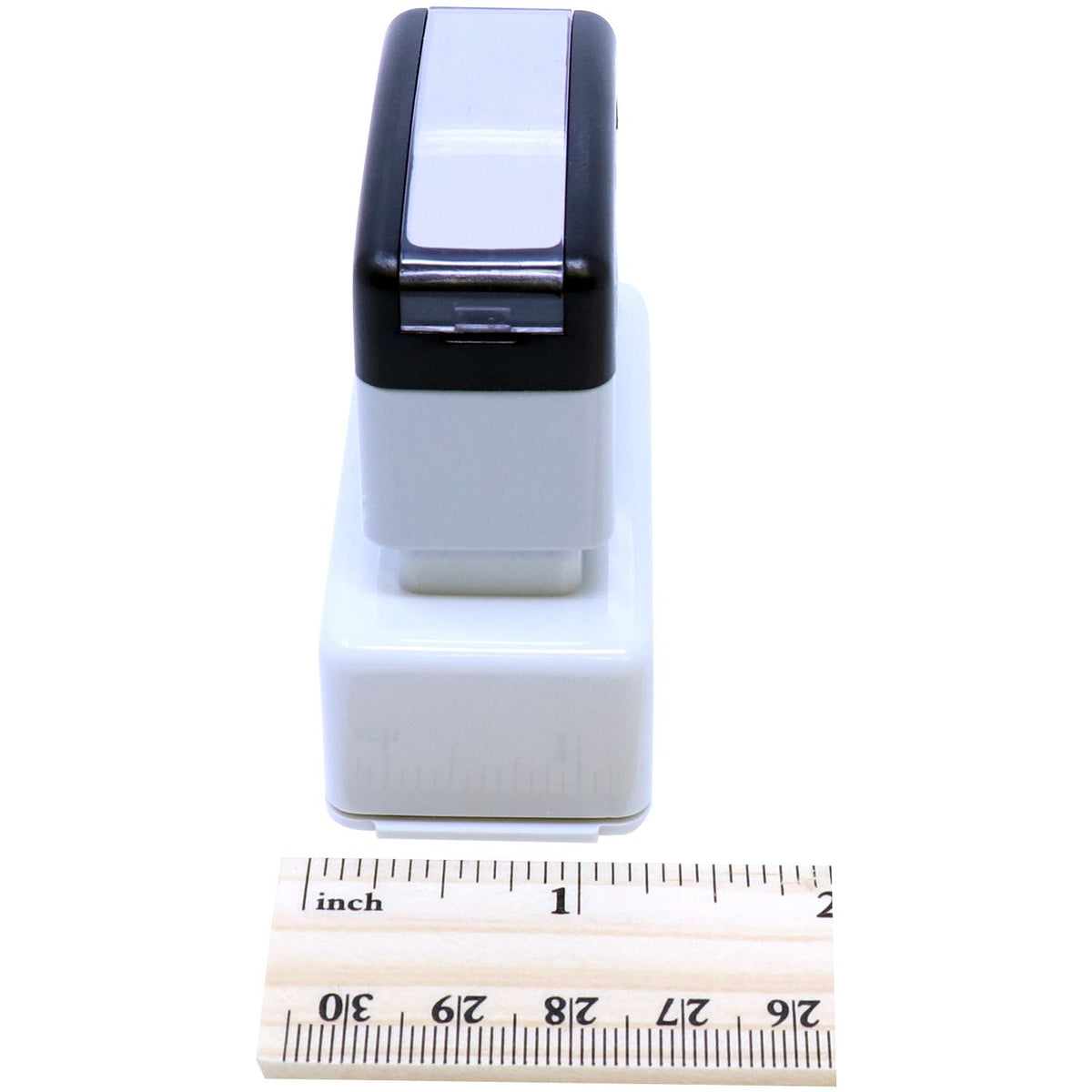 Close-up of compact black-and-white electronic device on an inch ruler, showing portable accessory dimensions for sale.