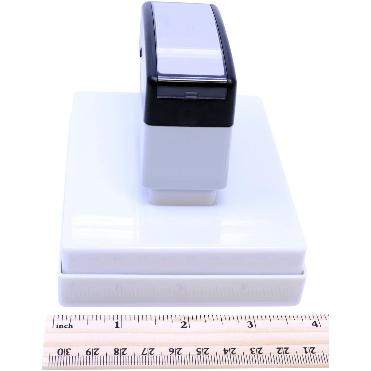 Compact ink stamp head on white base, shown with an inches ruler for accurate product size measurement reference.