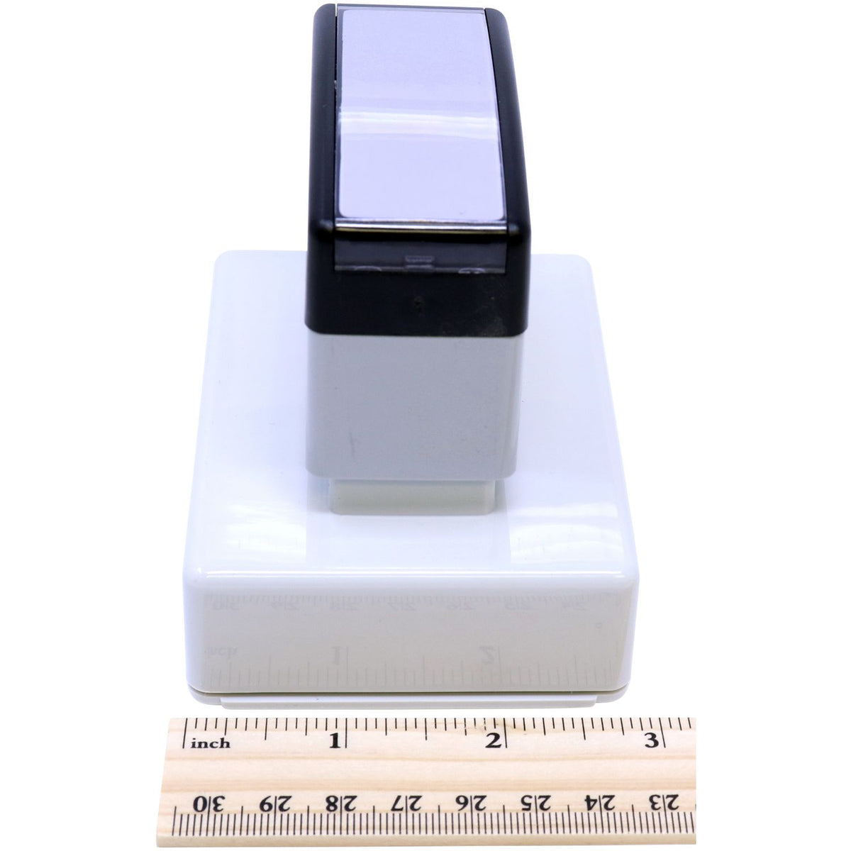 Measured phone charging dock base with black cradle and white housing, shown on ruler for size reference in inches.