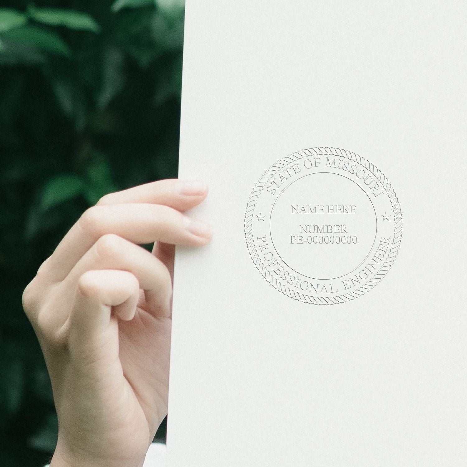 Hand holding a Missouri Professional Engineer certificate with embossed seal and name field on white paper.