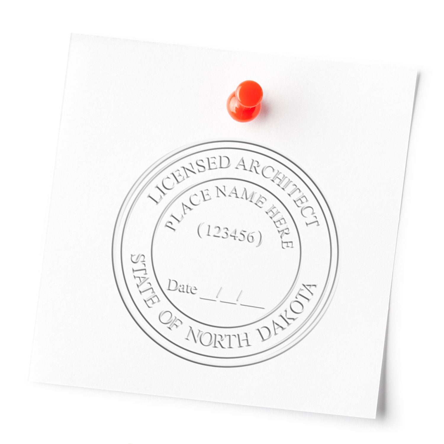 Embossed Licensed Architect seal from North Dakota on white paper pinned with a red pushpin.