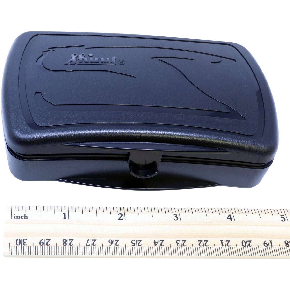 Black Brunny plastic storage case with latch, shown with inch ruler for size reference.
