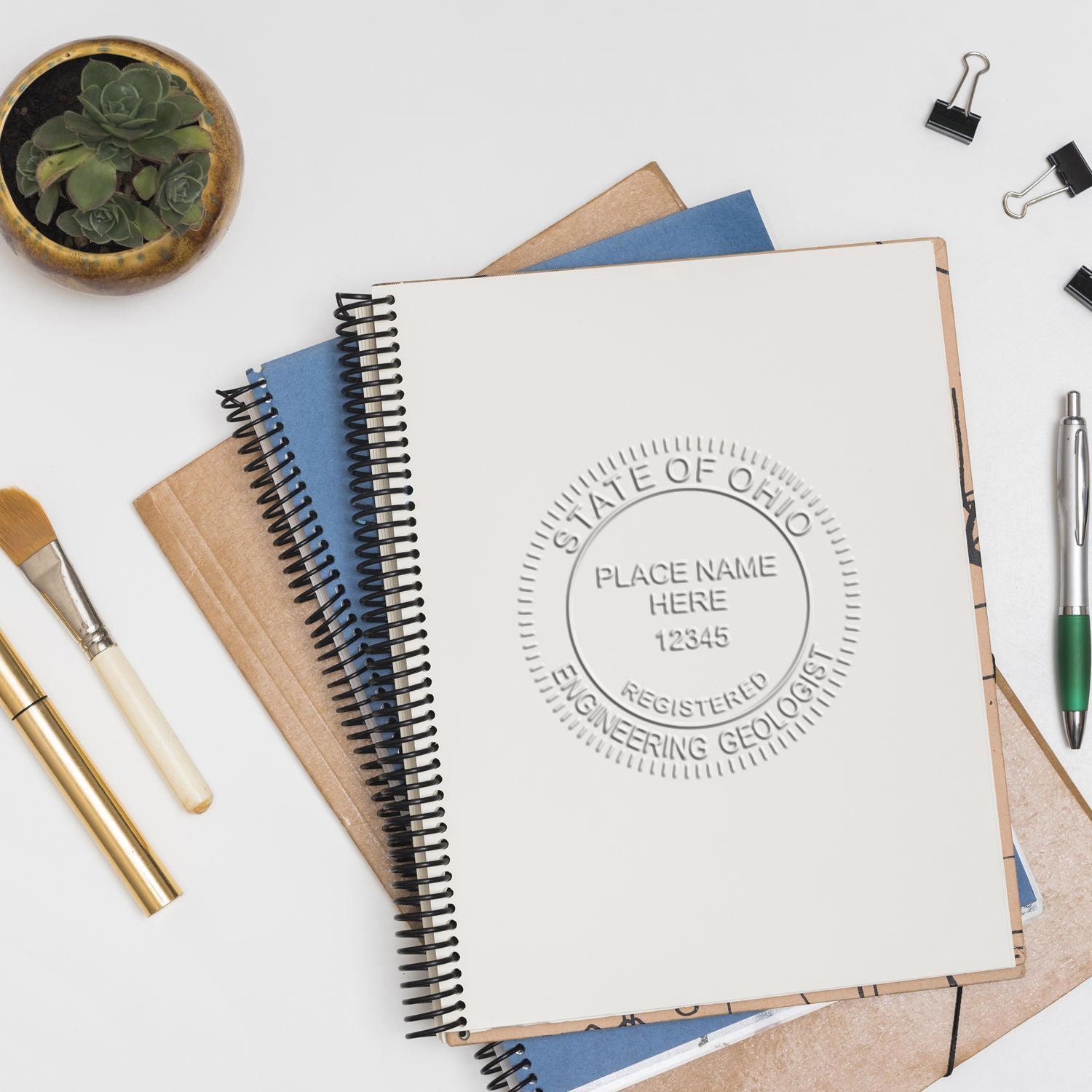Flat lay of custom spiral notebooks and stationery with embossed Ohio registered engineer geologist seal mockup.