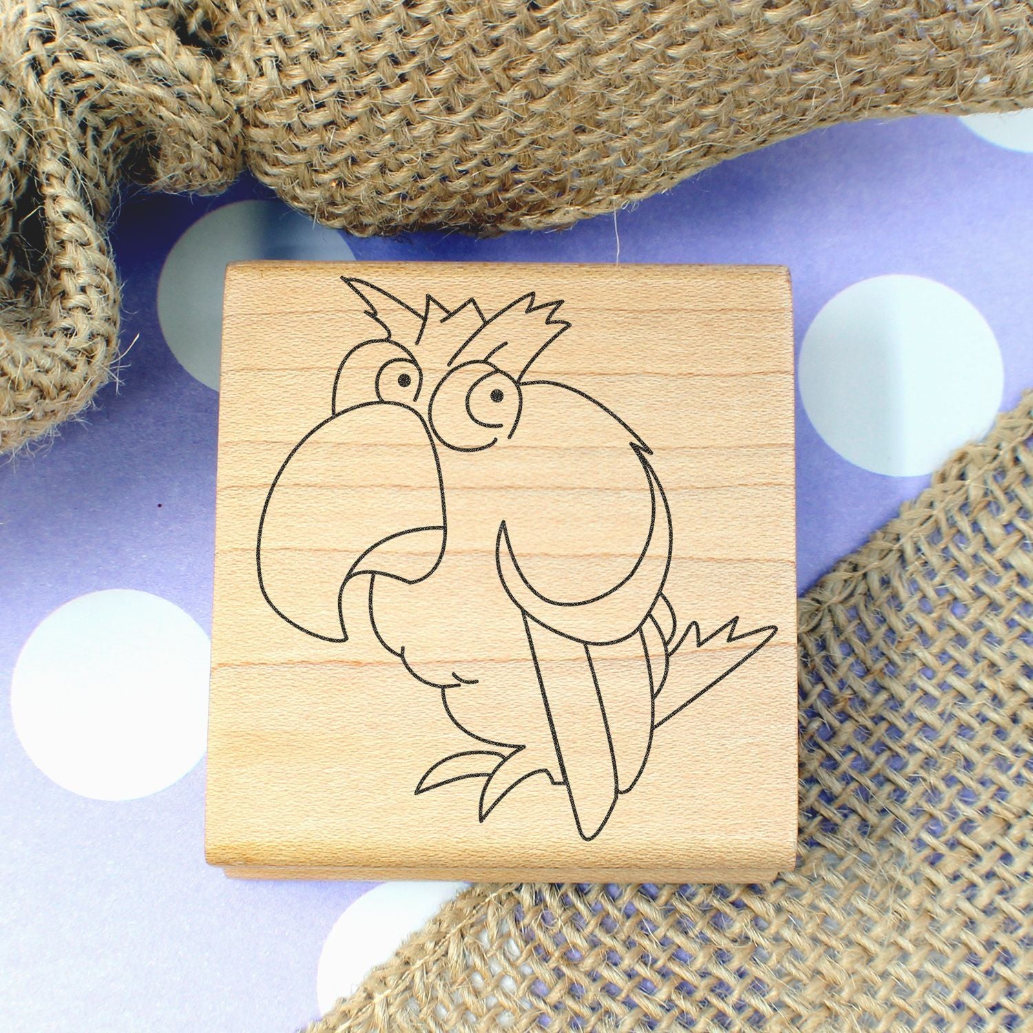 Wooden parrot rubber stamp with cartoon bird design on burlap background