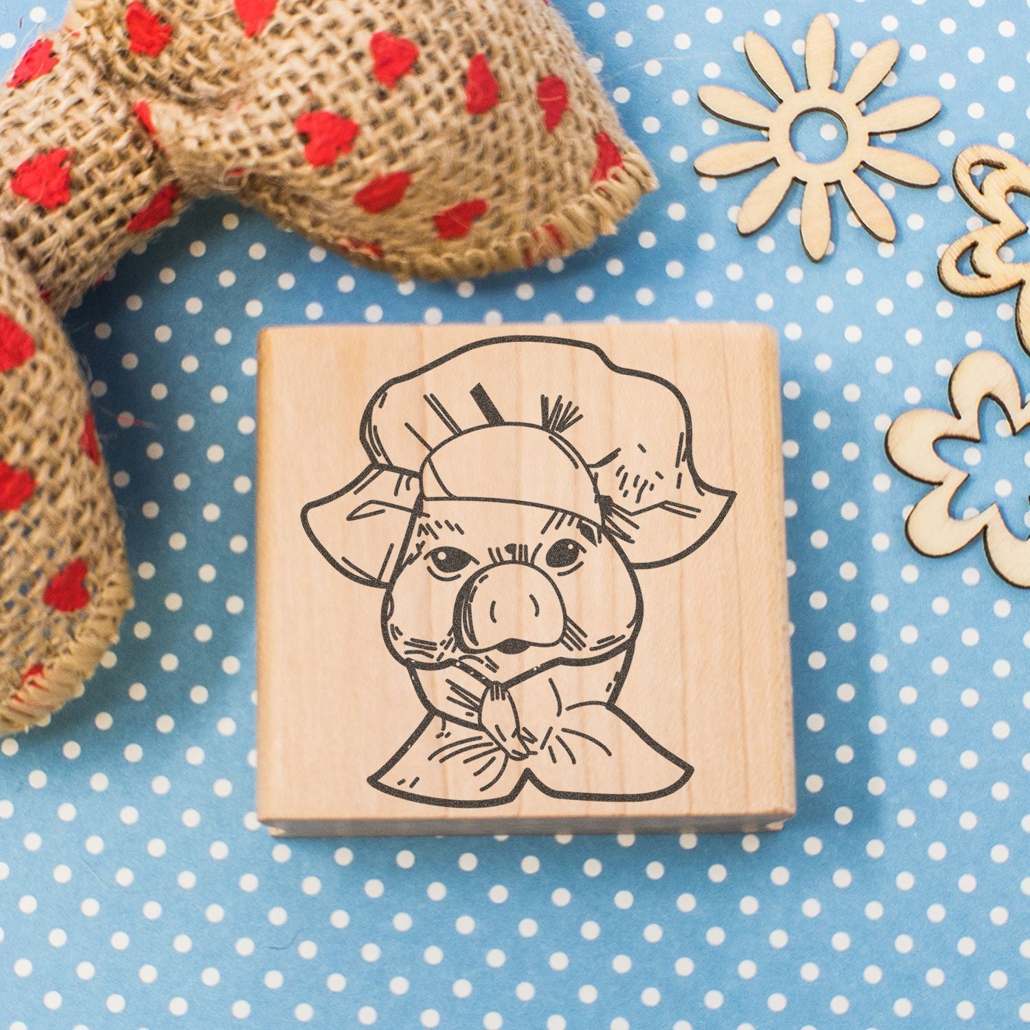 Wooden rubber stamp with hand-drawn pig illustration on blue polka dot background, craft and DIY decor supplies
