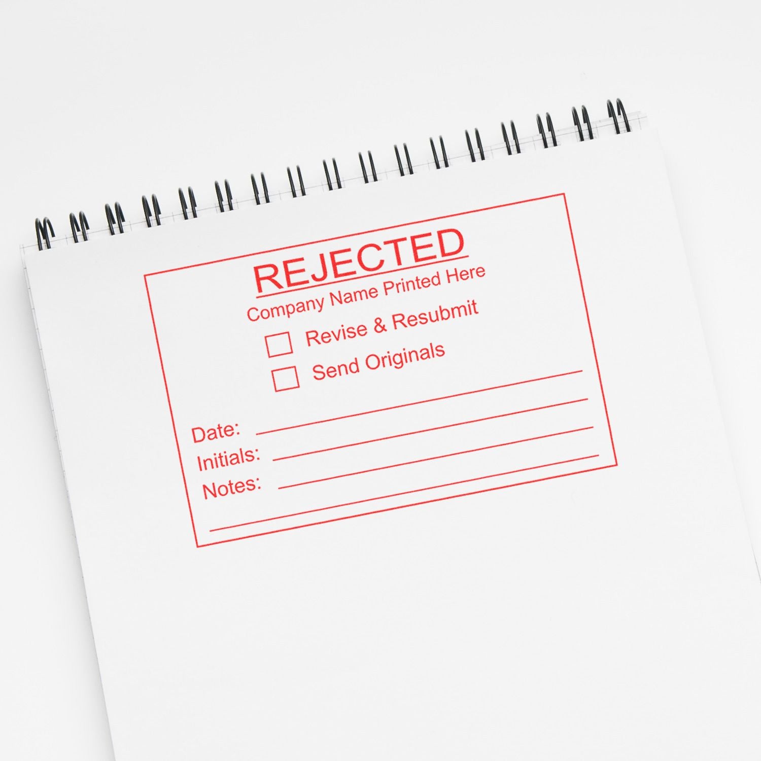 Rejected stamp on spiral notebook page with red revise and resubmit form on white background