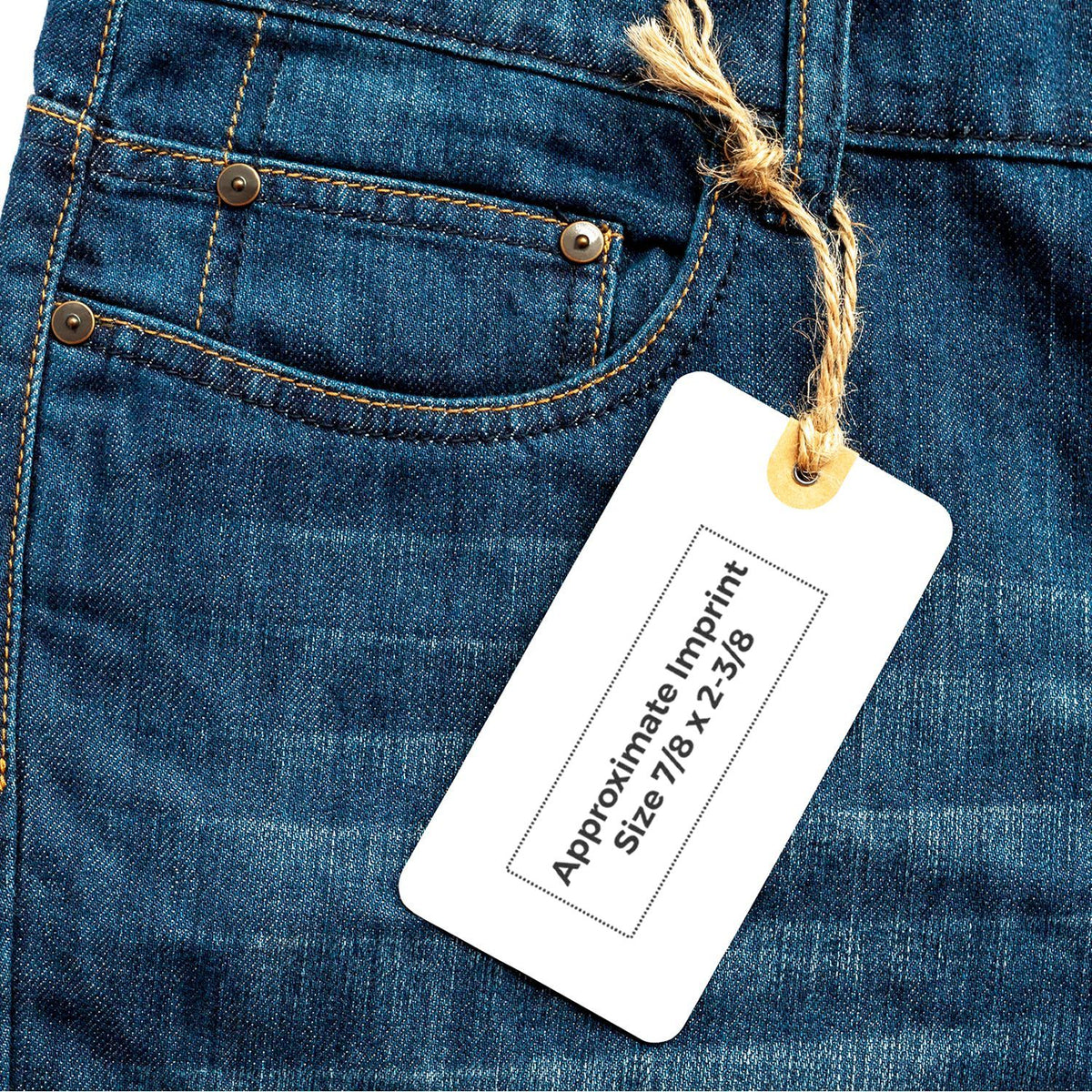 Close-up of blue denim jeans back pocket with blank clothing tag showing approximate imprint size 7/8 x 2-3/8.