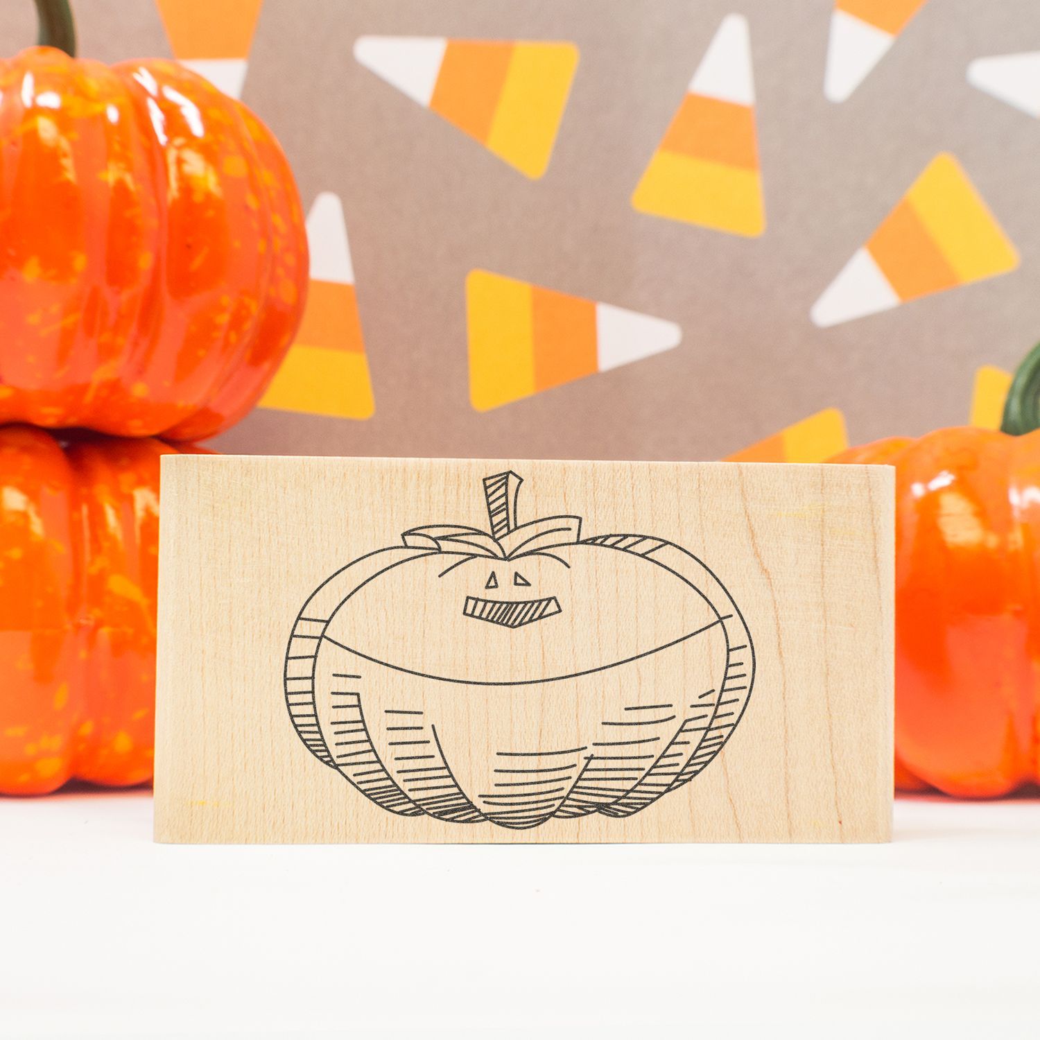 Wooden pumpkin stamp with Halloween candy corn background and orange decorative pumpkins