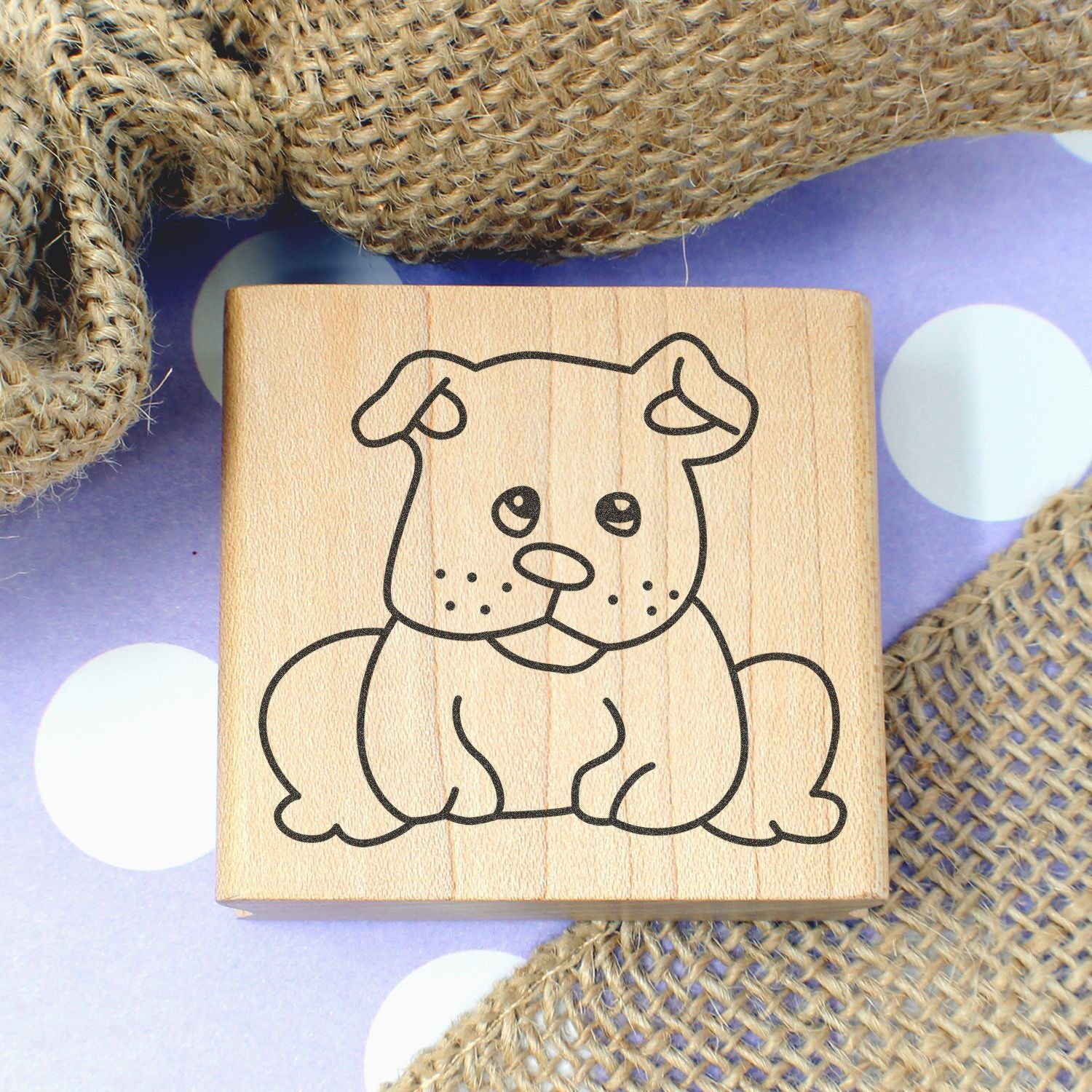 Cute dog stamp on a wooden block with rustic burlap and polka dot background, perfect for pet-themed crafting and DIY projects.