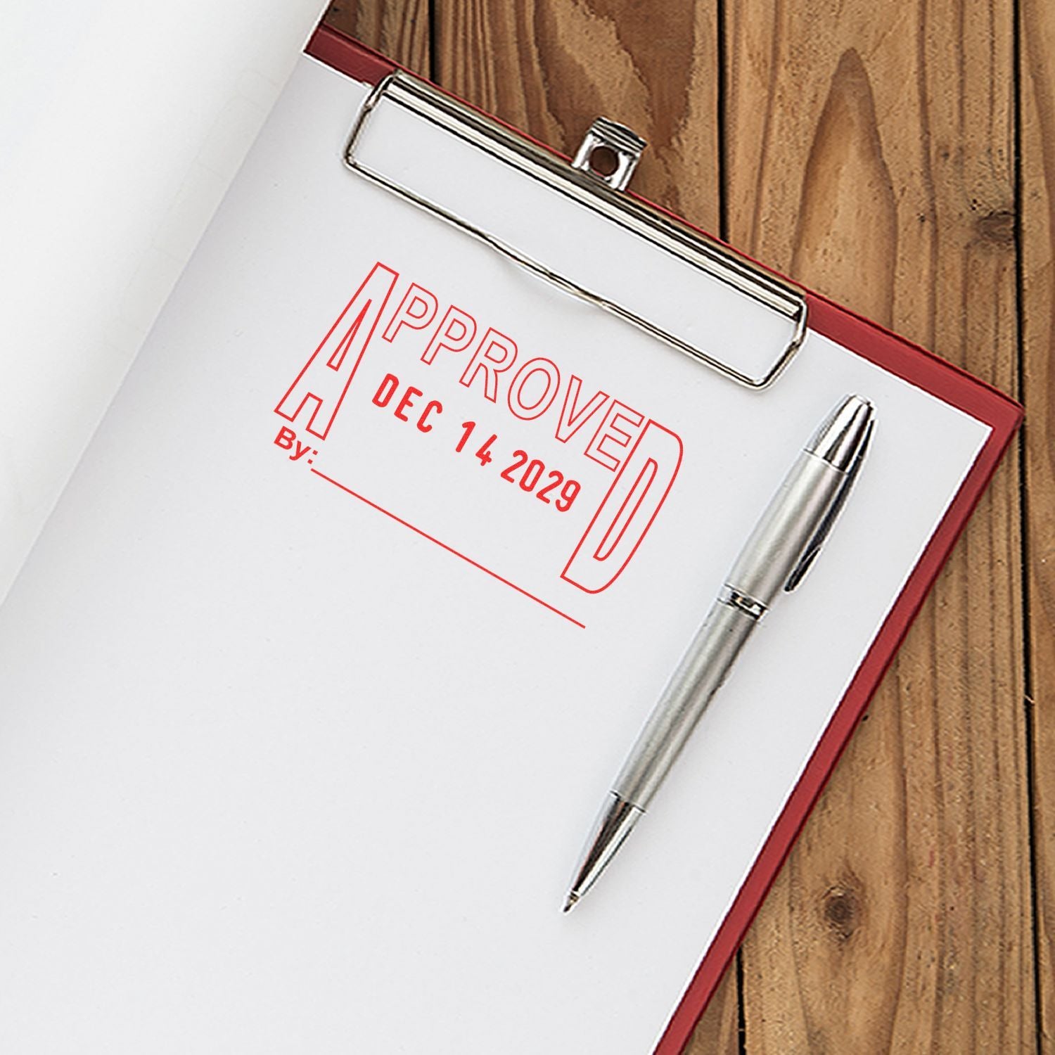 Approved stamp on clipboard with pen on wooden desk, business document sign-off concept.