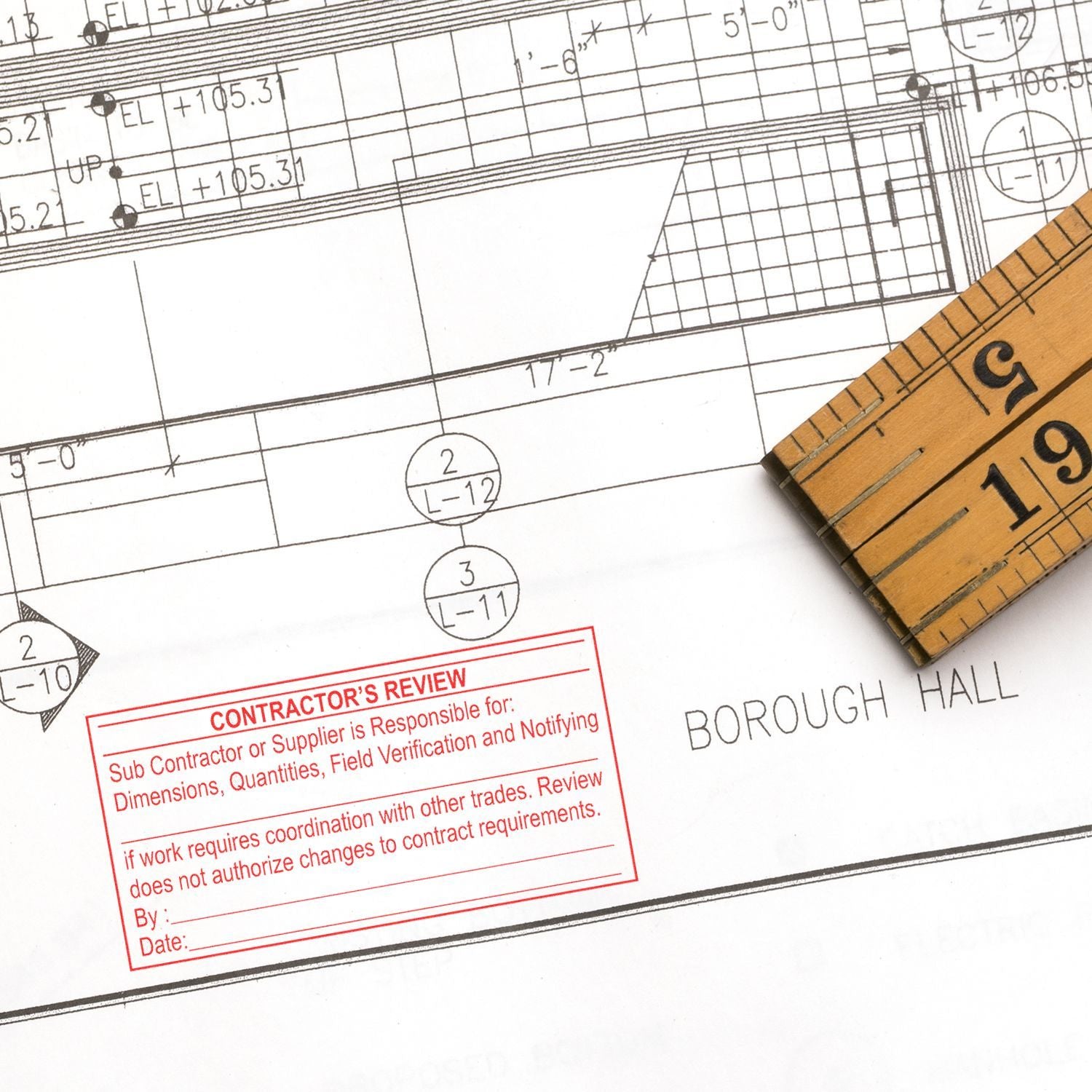 Architectural blueprint with measuring tape and contractor review stamp for a construction project at Borough Hall.