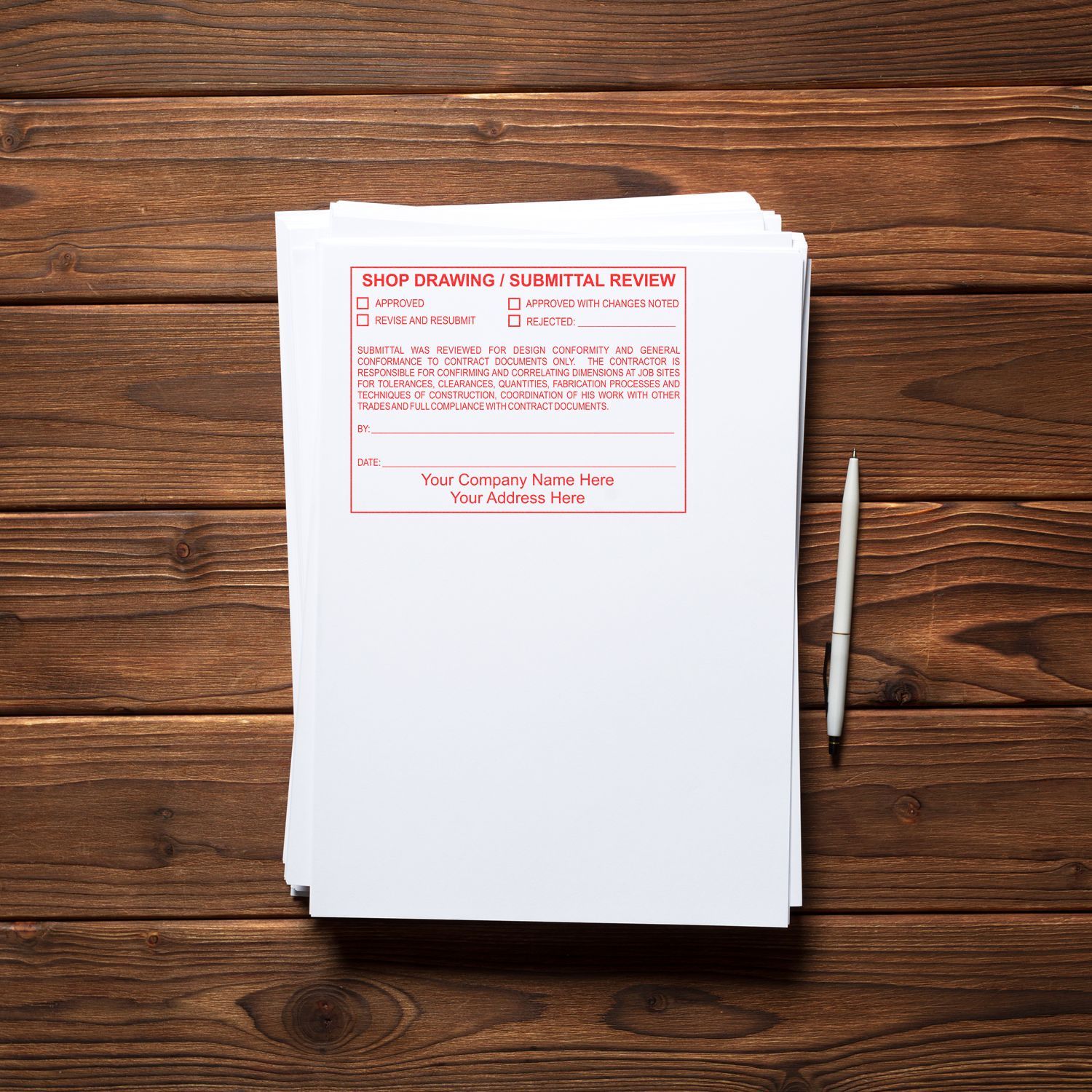 Stack of shop drawing submittal review forms on a wooden desk with pen, construction document approval paperwork.