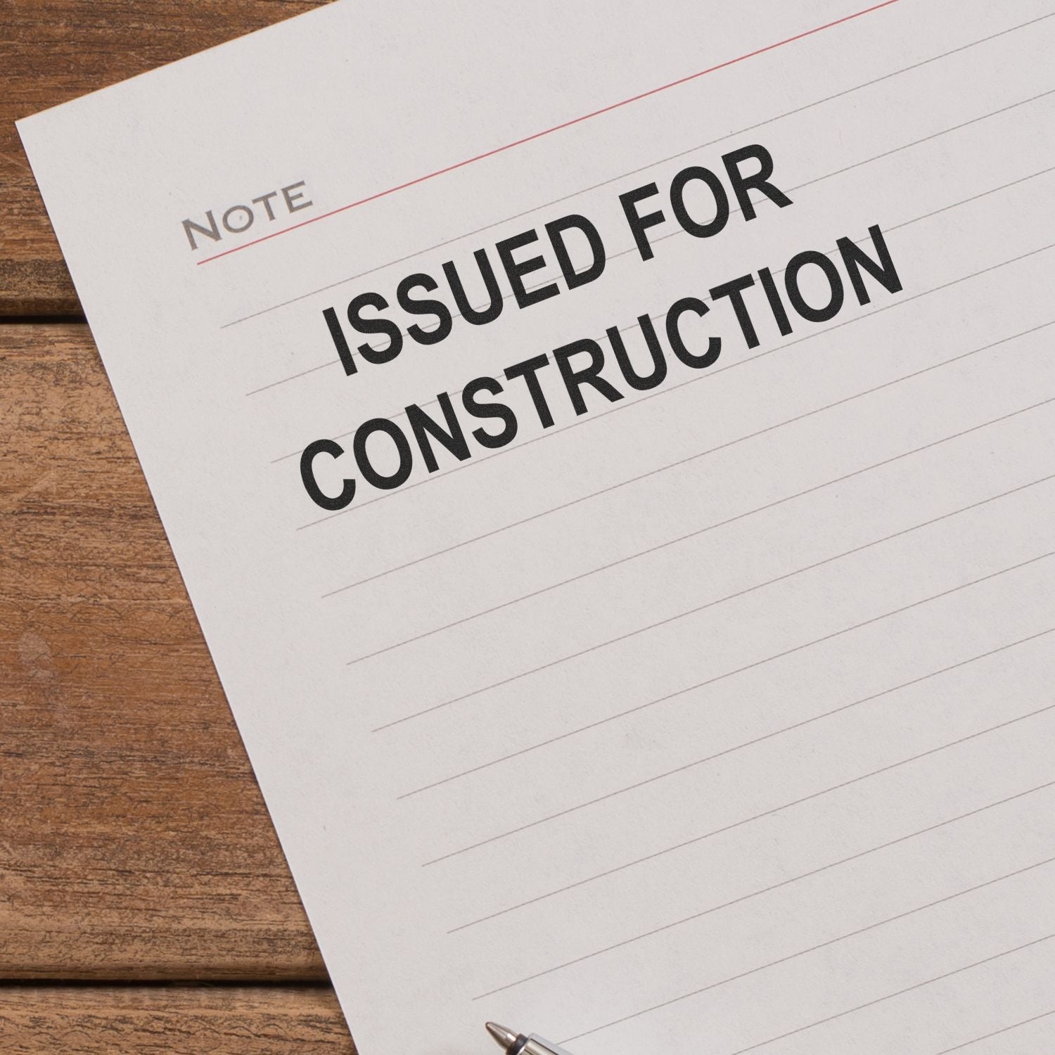Close-up of a note pad with Issued for Construction text on a wooden desk, concept for construction approval and project documentation.
