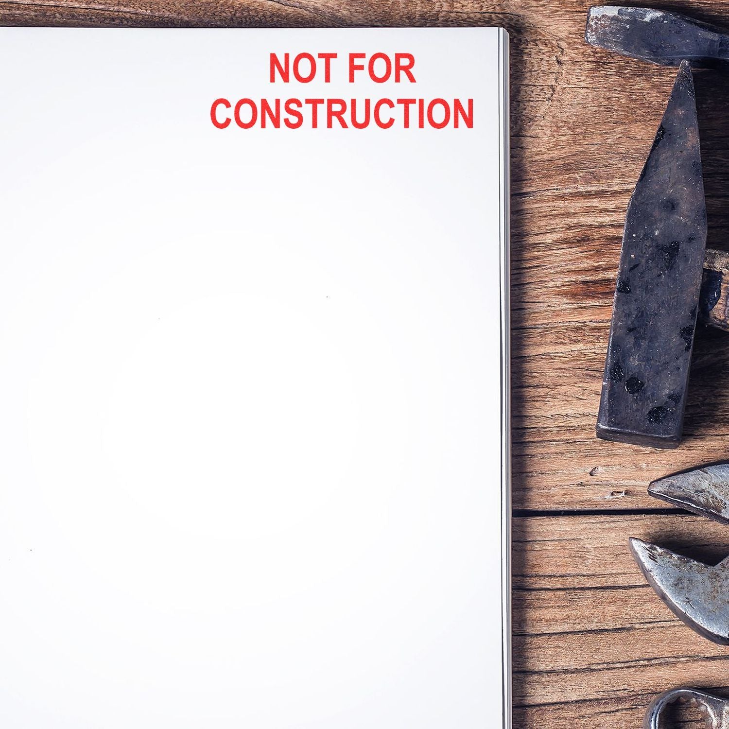 Blank notebook page with Not for Construction text beside hammers on a wooden workbench, construction warning concept.