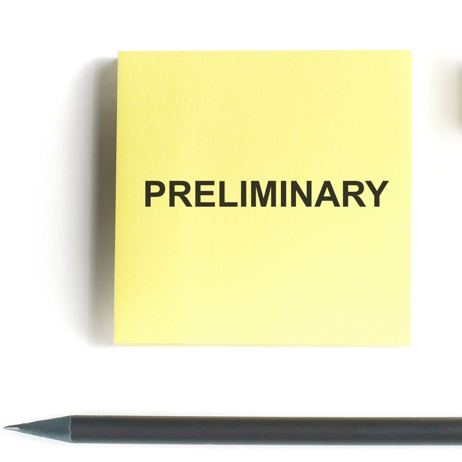 Yellow sticky note labeled PRELIMINARY with pencil on white background, simple office concept image.