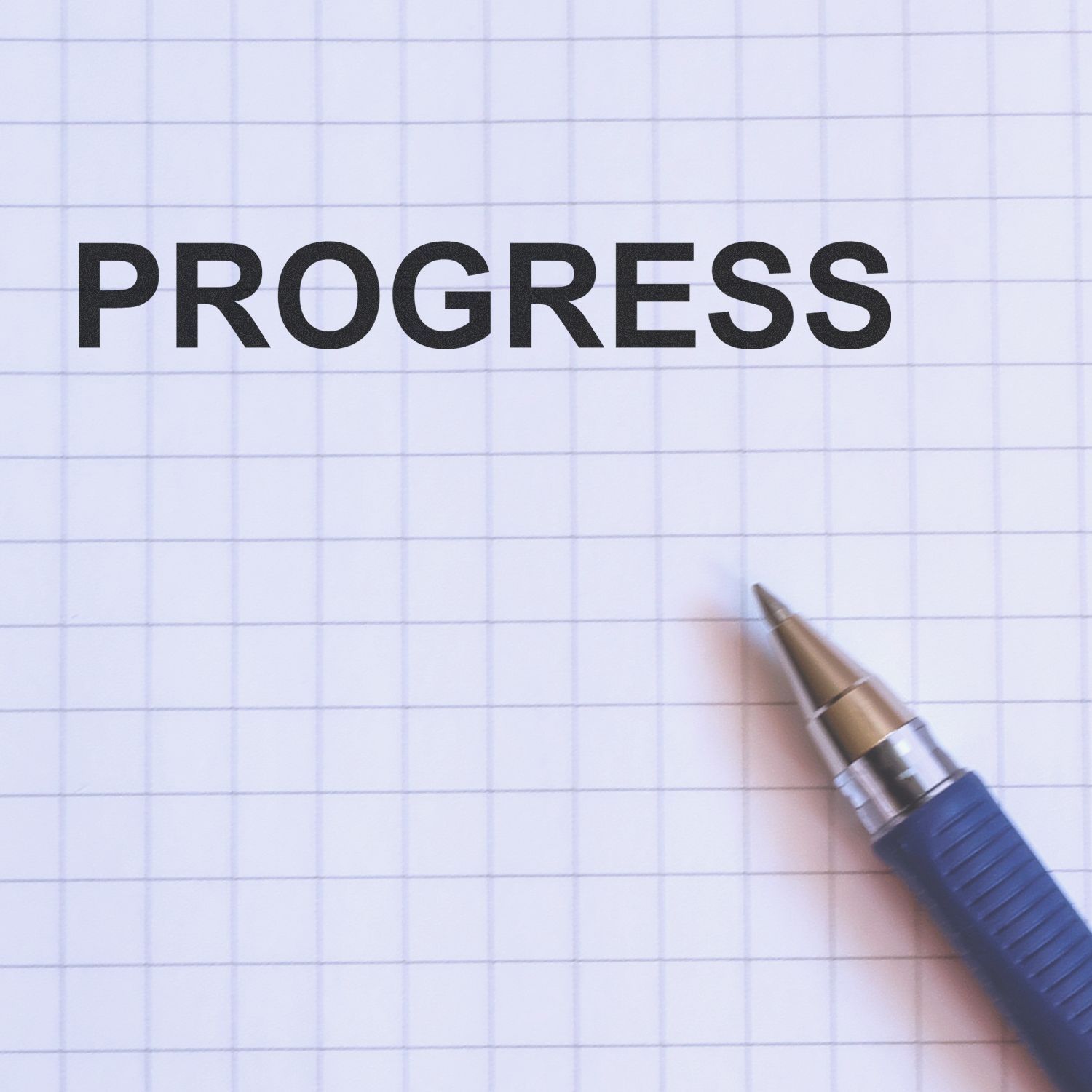 Word PROGRESS on graph paper with a pen, symbolizing business growth, goal setting, and productivity.