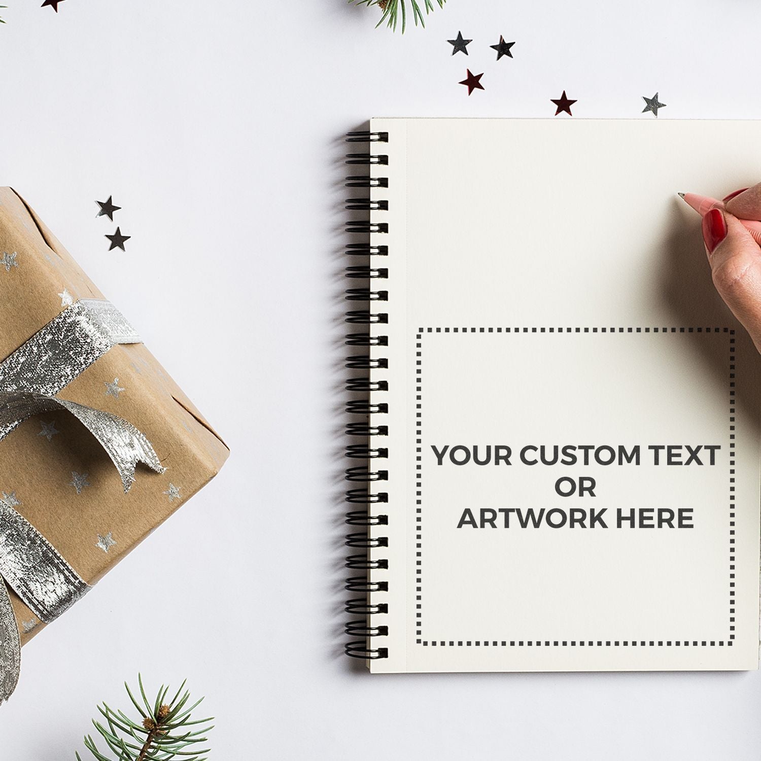 Blank Christmas notebook with custom text area, star decorations and pine, hand holding pen for holiday messages