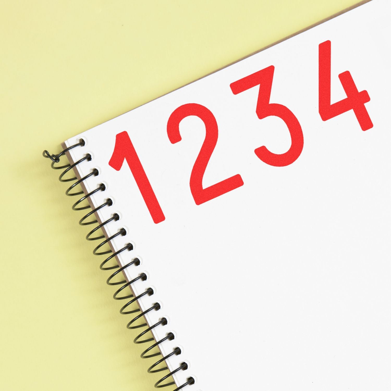Spiral-bound notebook with red 1234 numbers on a white page over a yellow background.