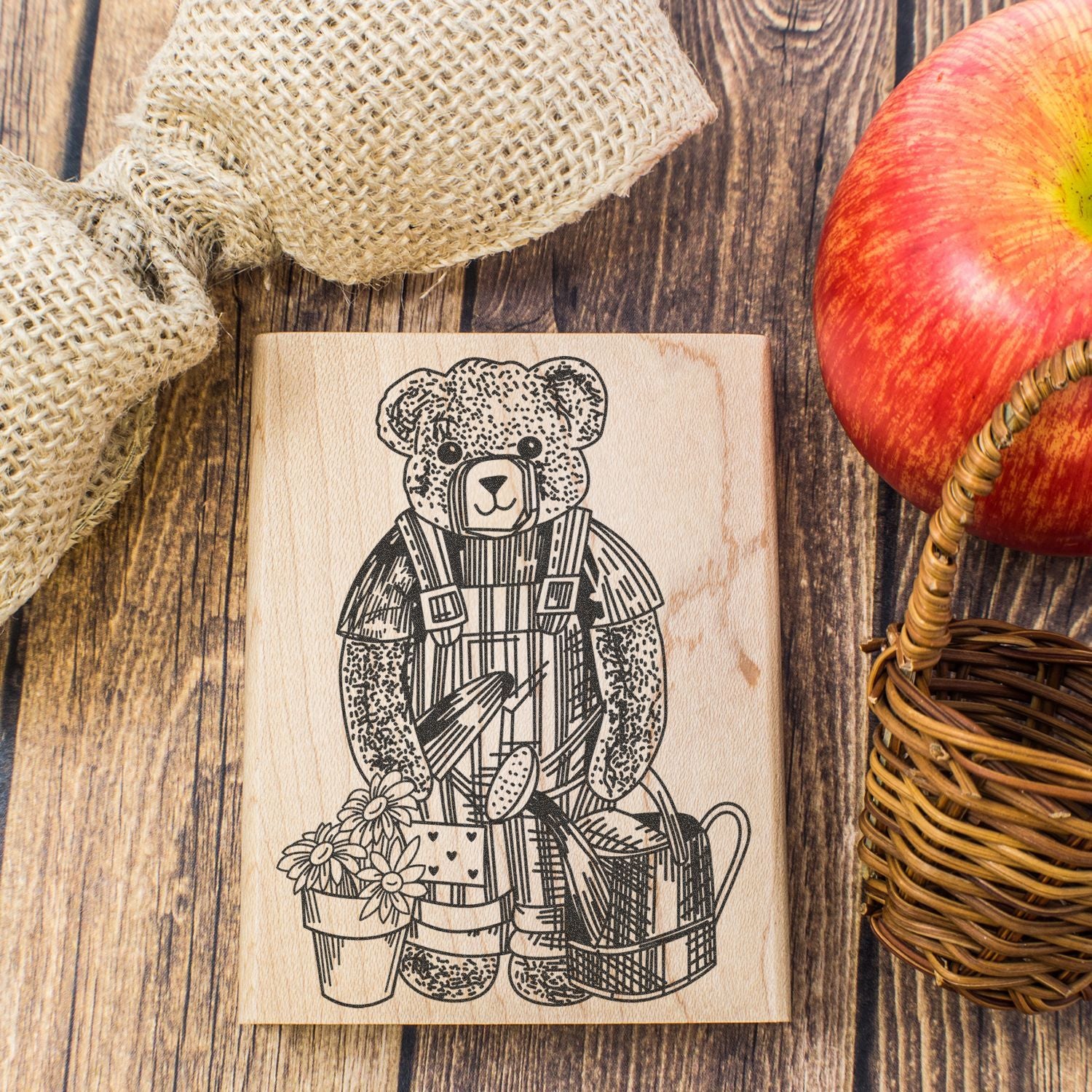 Rustic wooden bear stamp with flowers, apple, and burlap on a farmhouse table setup