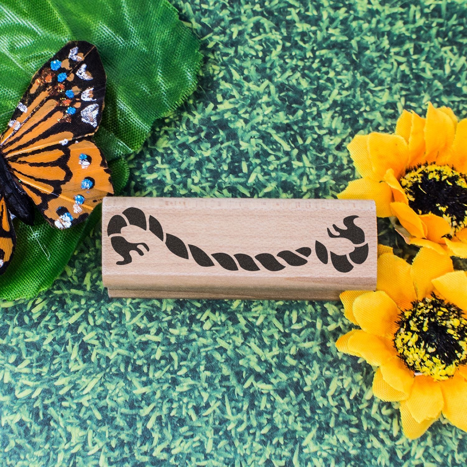Decorative butterfly rubber stamp with sunflower and butterfly craft background on green floral fabric.