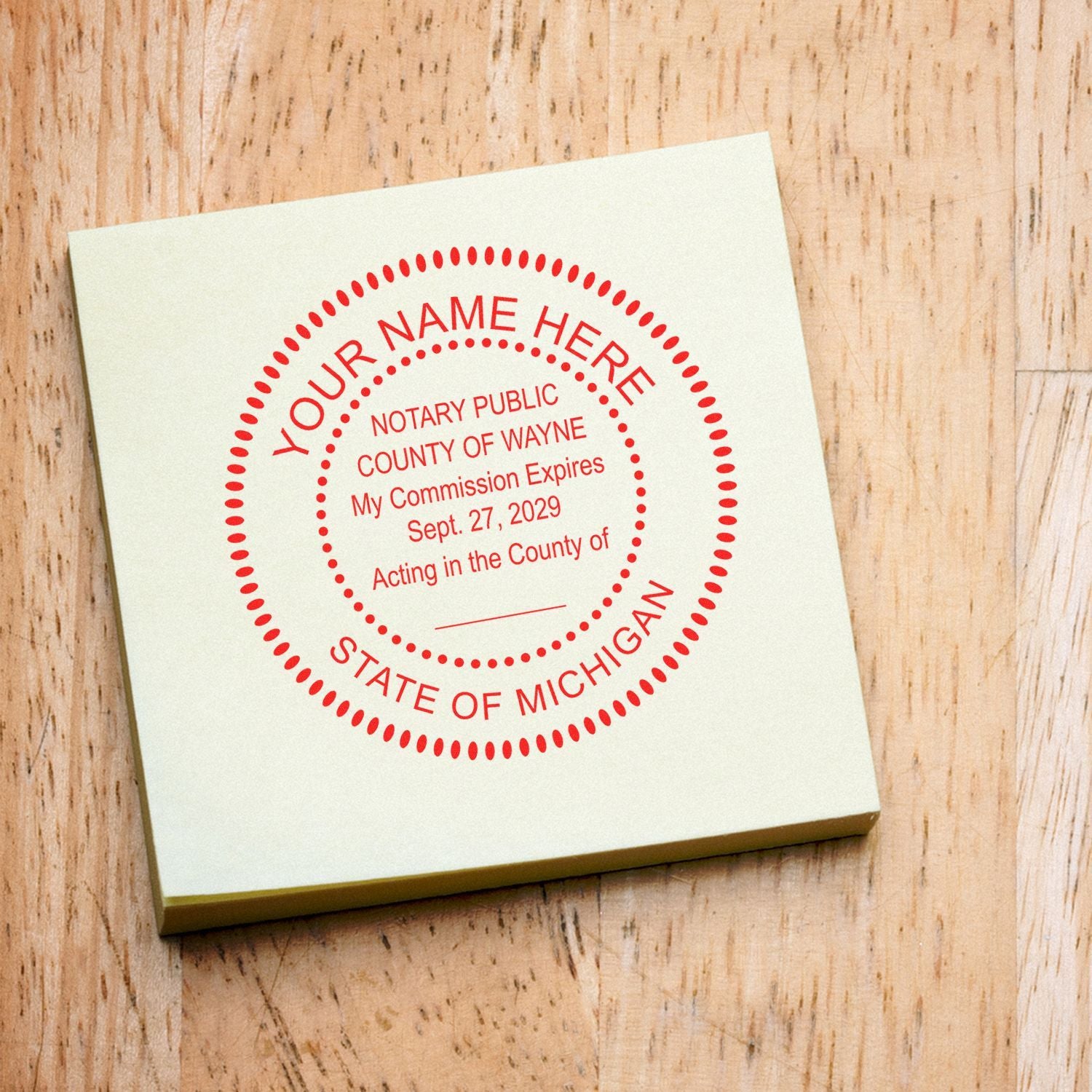 Custom notary public seal stamp for State of Michigan on a square note over a wooden background.