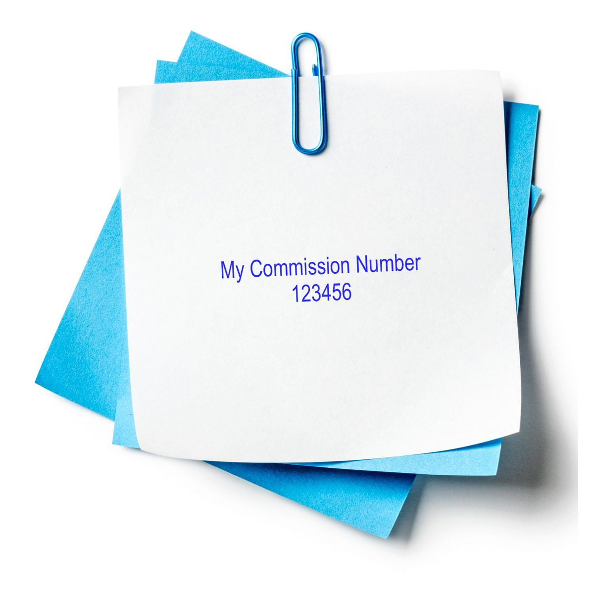 White note clipped with blue paperclip reading My Commission Number 123456 on layered blue sticky notes.