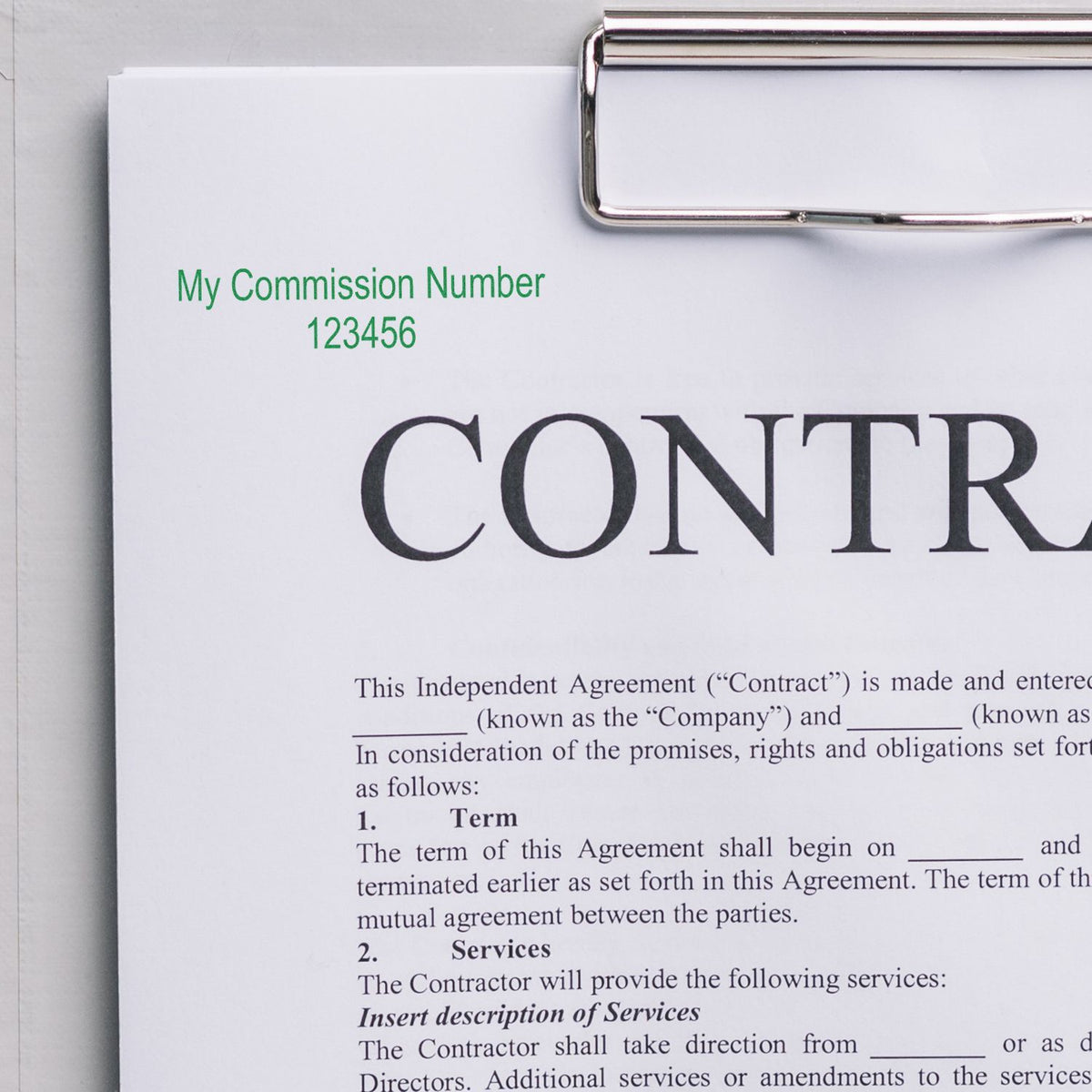 Independent contractor agreement on clipboard with commission number 123456, close-up of business contract form and legal document.