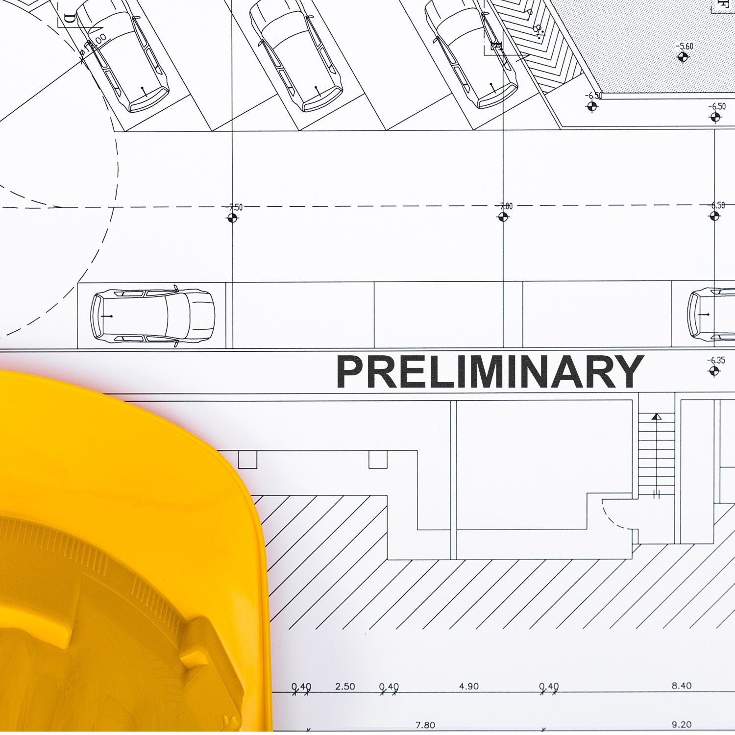 Yellow hard hat on preliminary architectural site plan with parking layout and cars, construction blueprint drawing.