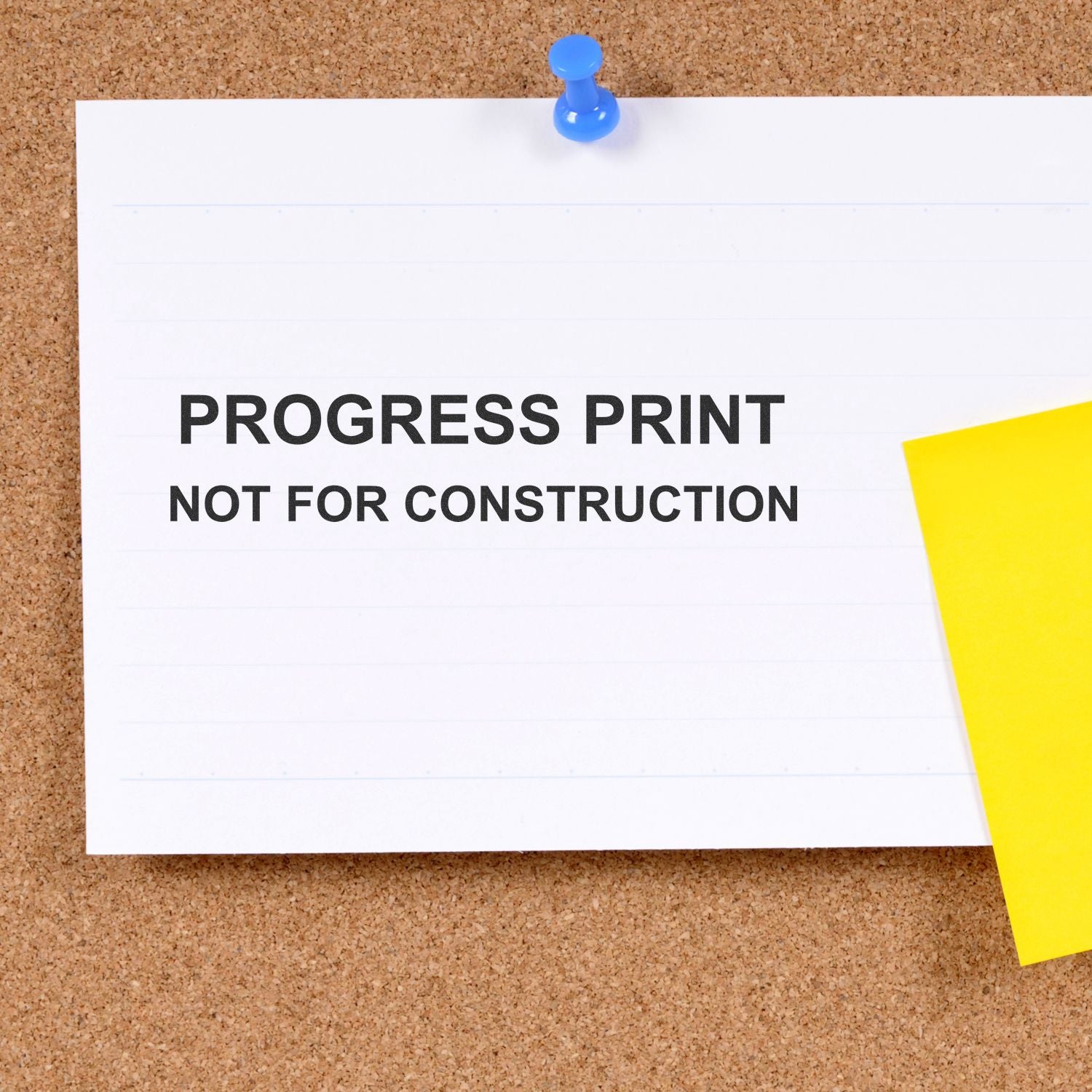 Progress print not for construction notice pinned on corkboard with blue pushpin and yellow note.