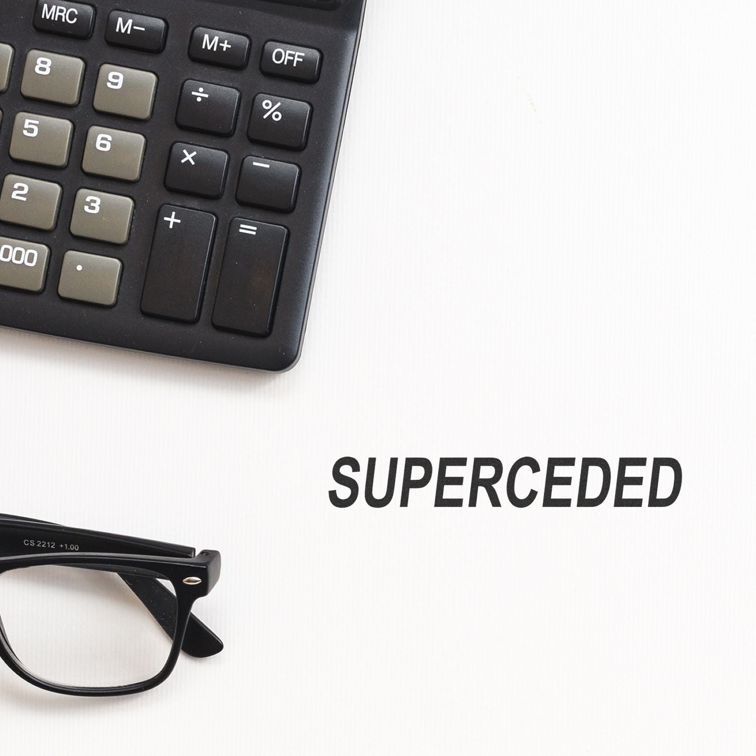 Calculator and eyeglasses beside a superseded document on a white background.