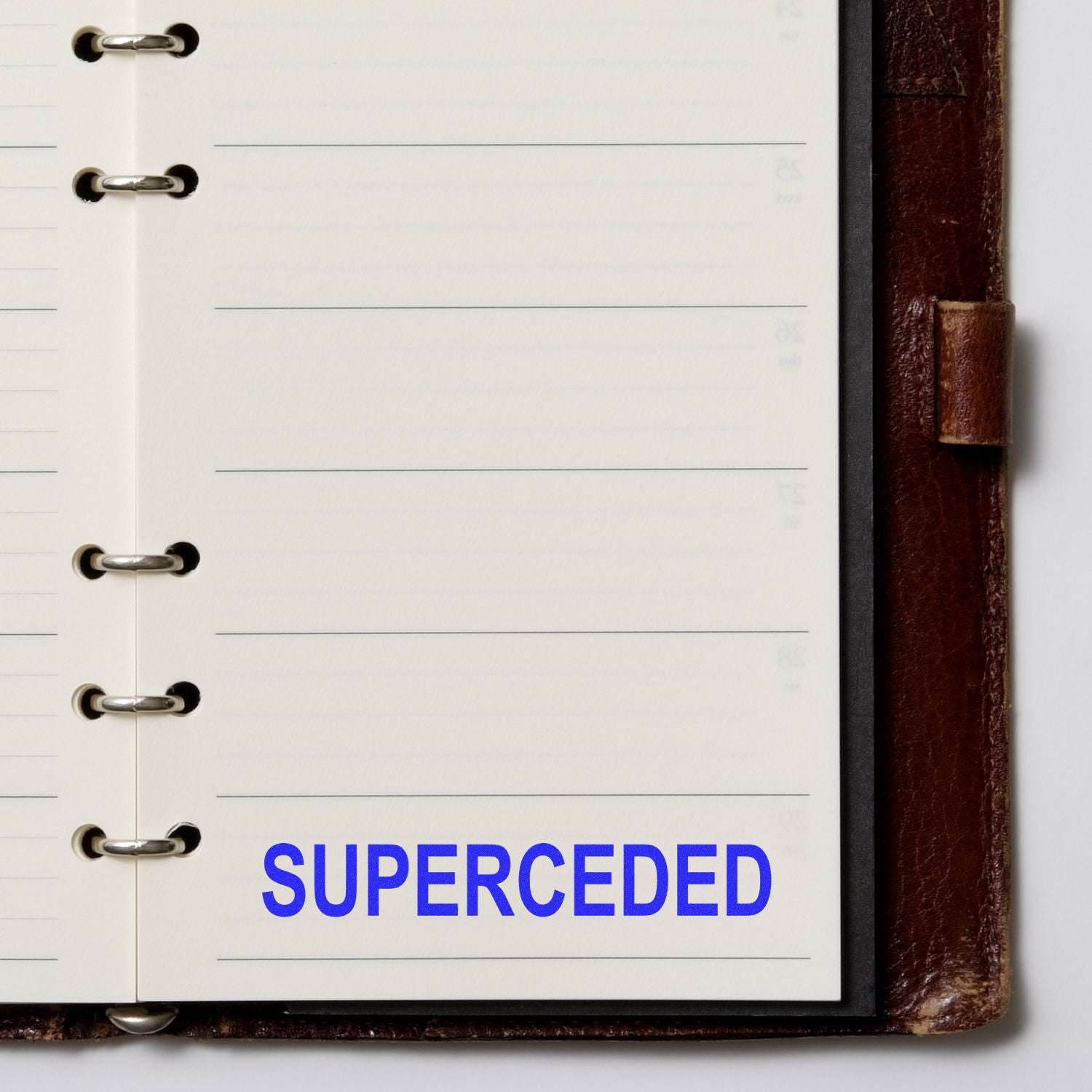 Open leather ring binder planner page with blank lined paper and blue SUPERCEDED label.